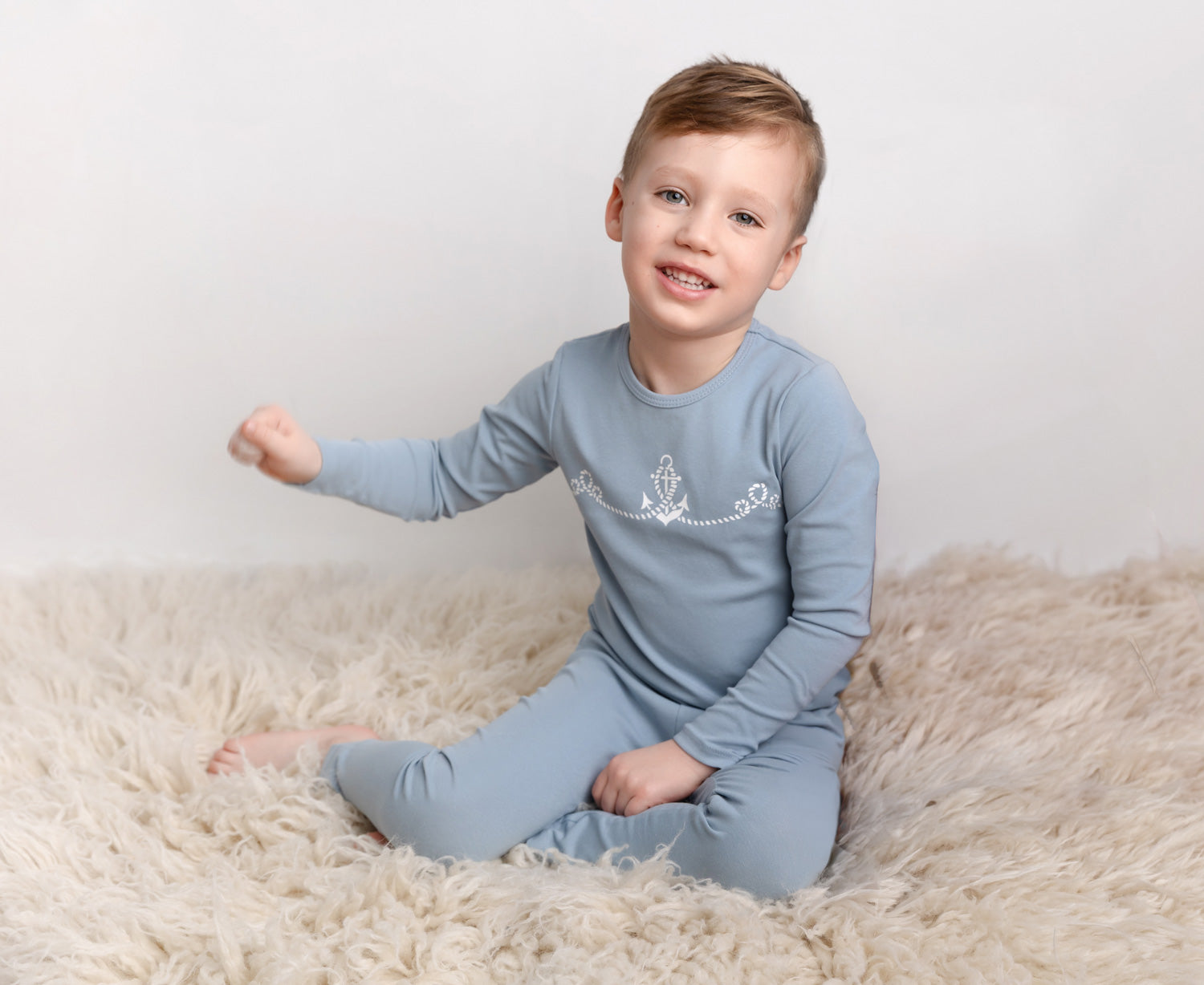 Happy boy in cozy blue pajamas playing with soft toys, perfect for winter nights and comfort.