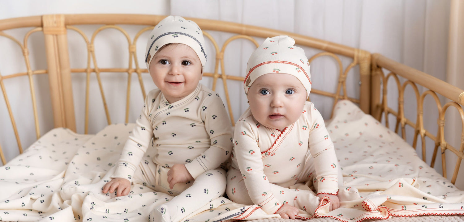 Adorable baby in floral outfit and matching hat, exploring a cozy room with striped pillow.