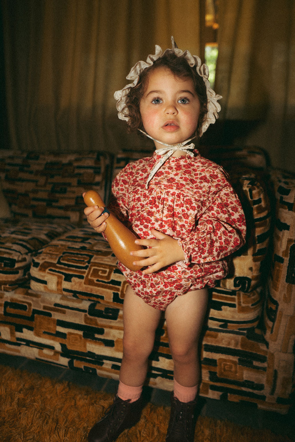 Two adorable infants wearing soft baby rompers, playing with toys on a cozy floor, showcasing stylish baby apparel.