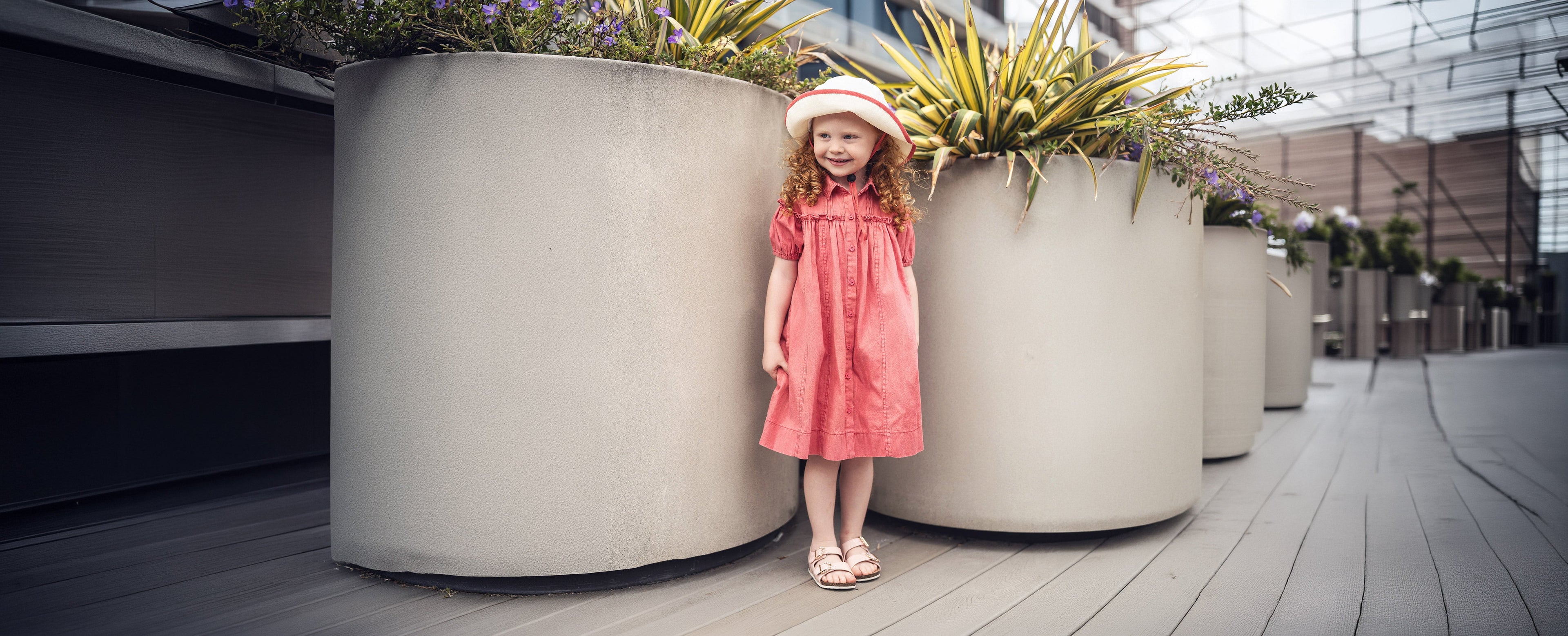 Girl wearing a hat and pink dress with ruffles
