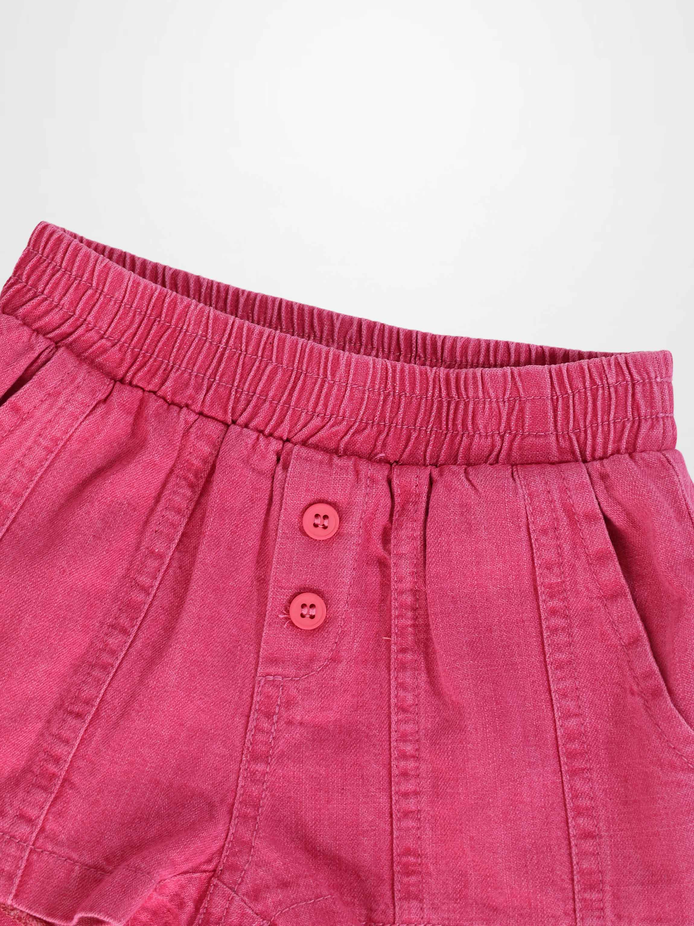 Paneled pink denim shorts with elastic waistband and two pink buttons.