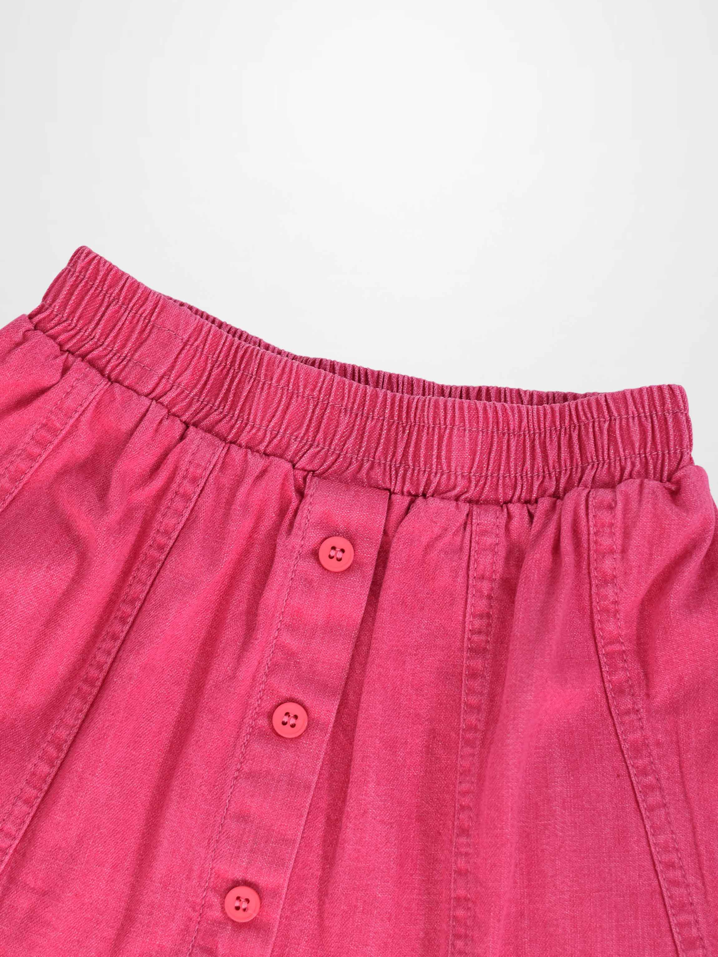 Paneled pink denim skirt with elastic waistband and pink front buttons.