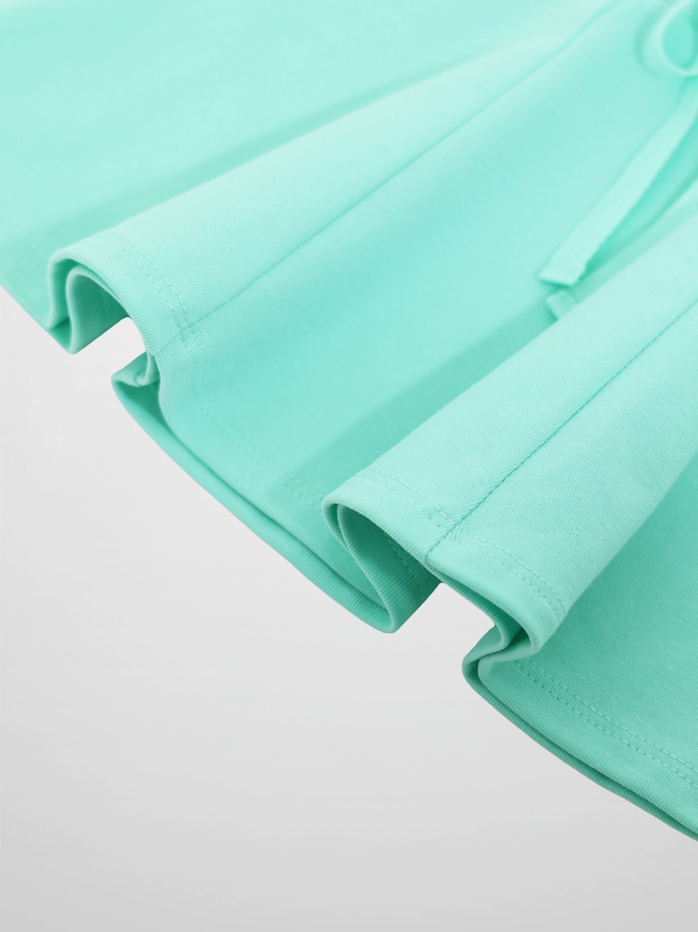 Mint green six-panel skirt close-up showing folded panels and stitching.