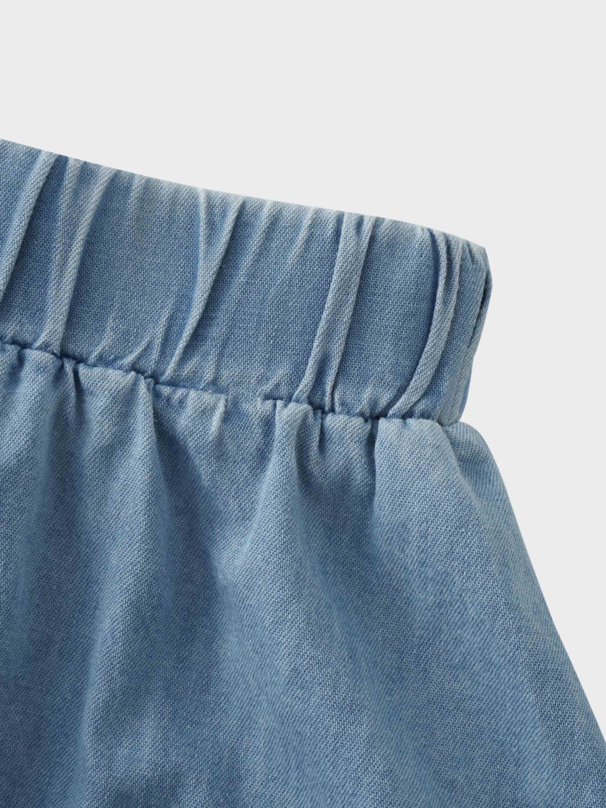 Elastic waist detail of a girls light denim skirt