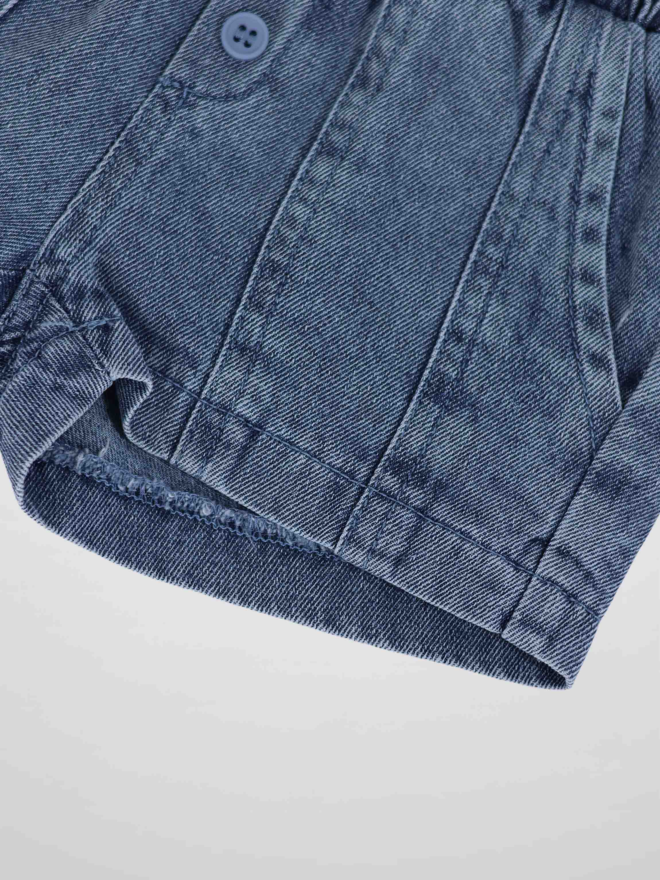 Paneled Shorts in blue denim, close-up of seam panels, button, and hem detail.
