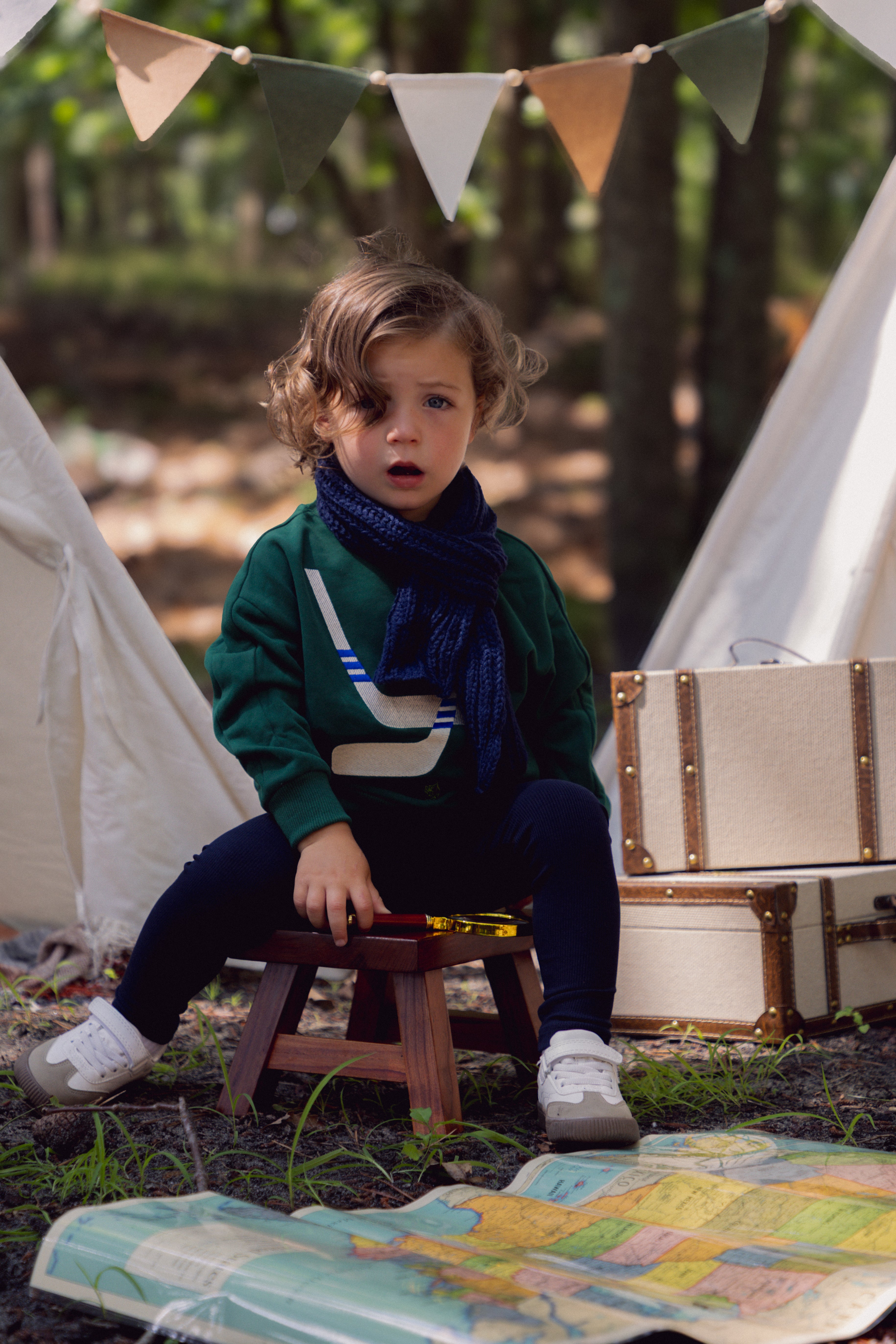 Boy wearing a dark green Hockey Sweatshirt with white and blue crossed-sticks embroidery and a green and blue puck