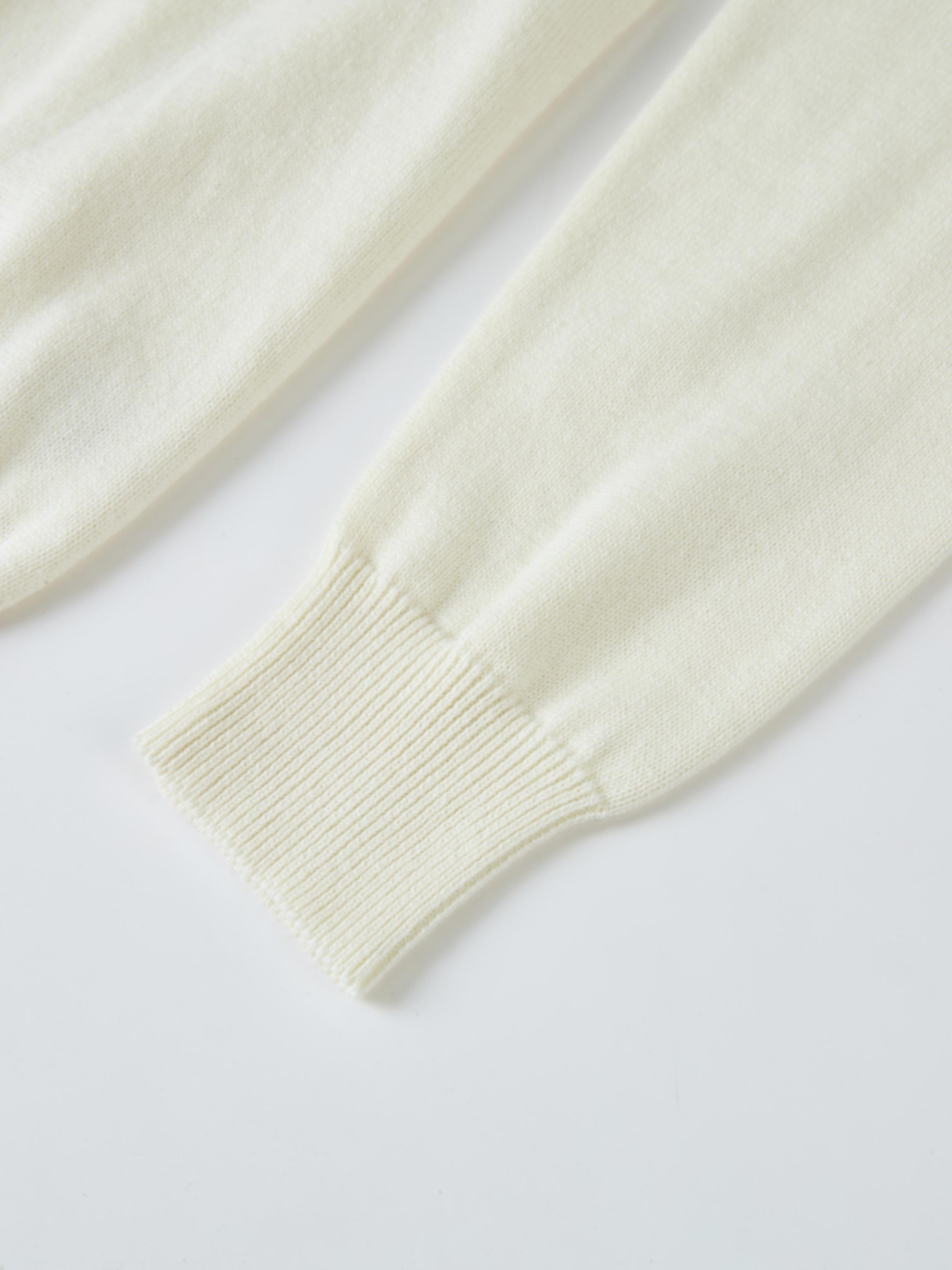 Ruffle Collar Knit Sweater by Adee in cream, close-up view of sleeve with ribbed cuff