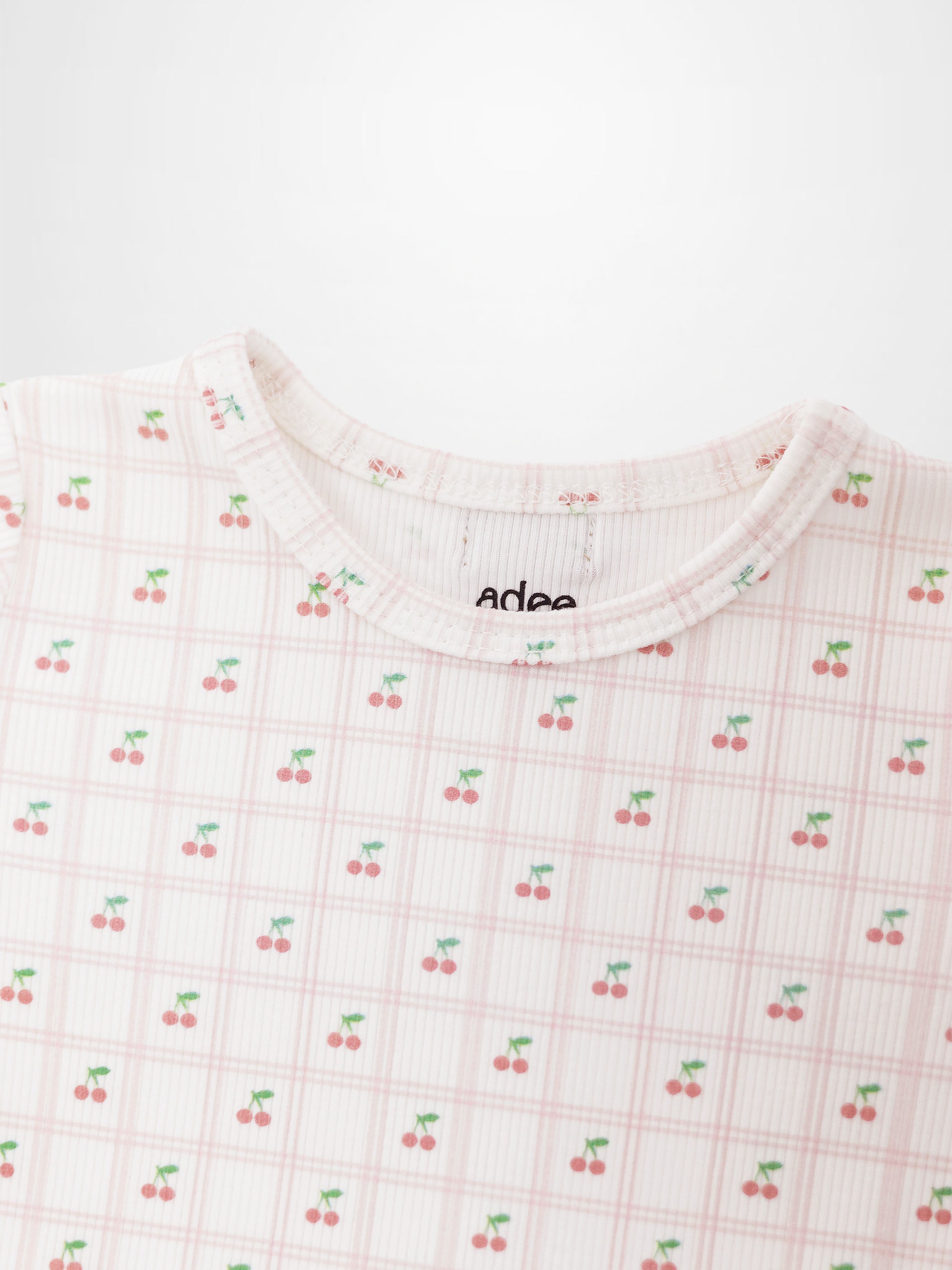Girls Cherry Window Pajamas by Adee, light pink plaid grid with tiny red cherries and green stems throughout.