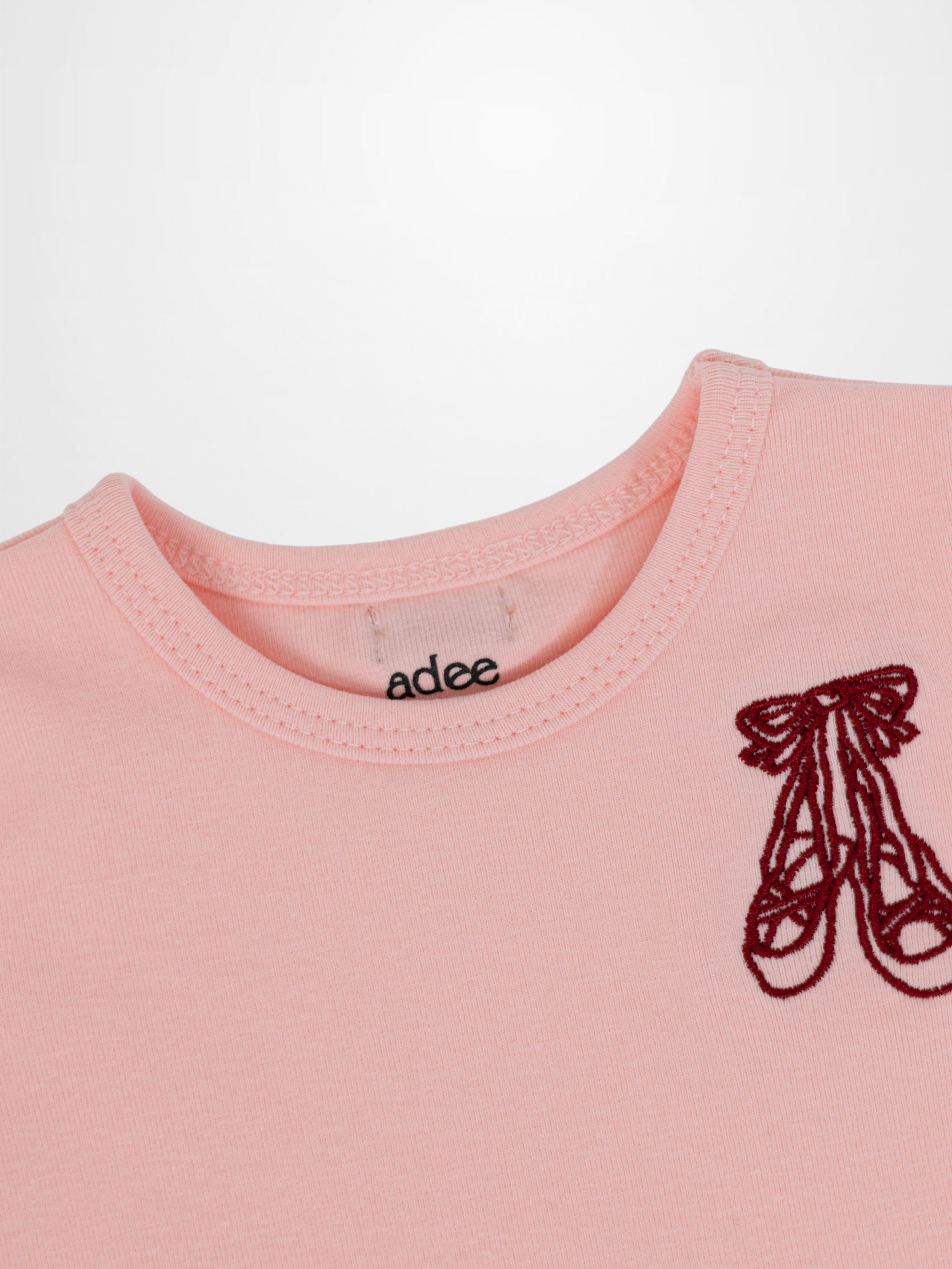 Short sleeve T-shirt by Adee in light pink with a red embroidered emblem.