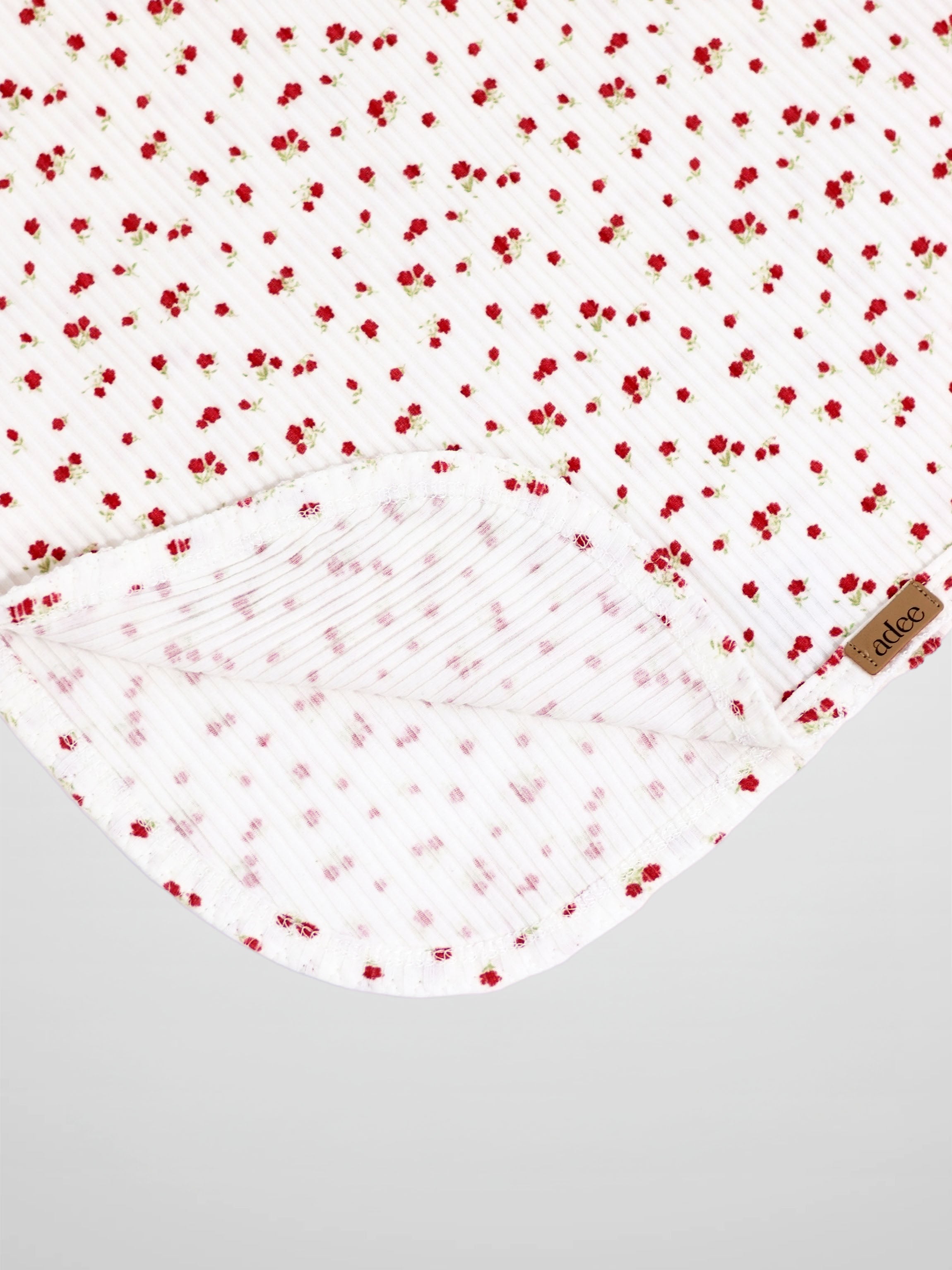 Red flower swaddle blanket for girls by Adee, a white receiving blanket with tiny red blooms.