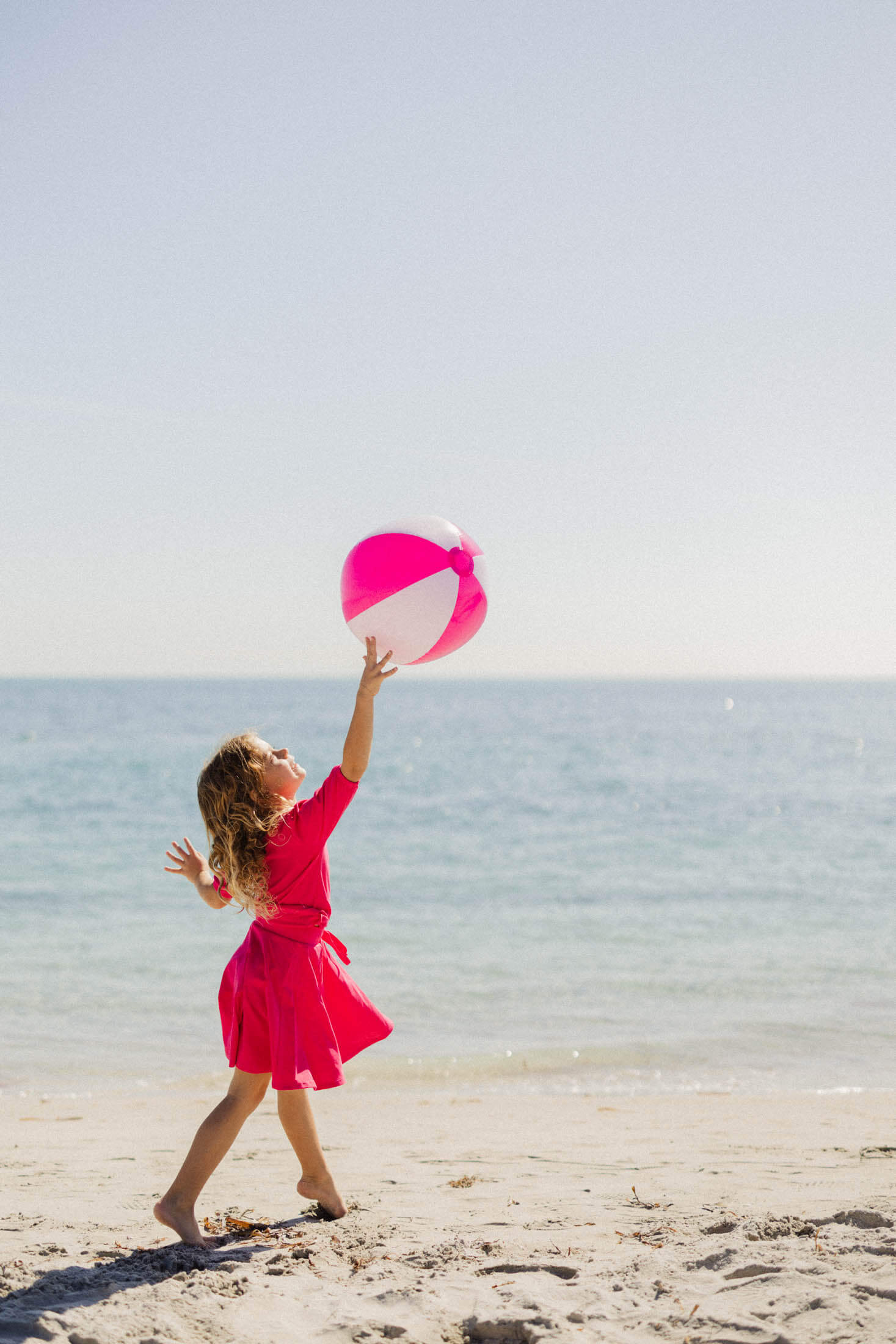 Girl in pink skirt playing beach ball