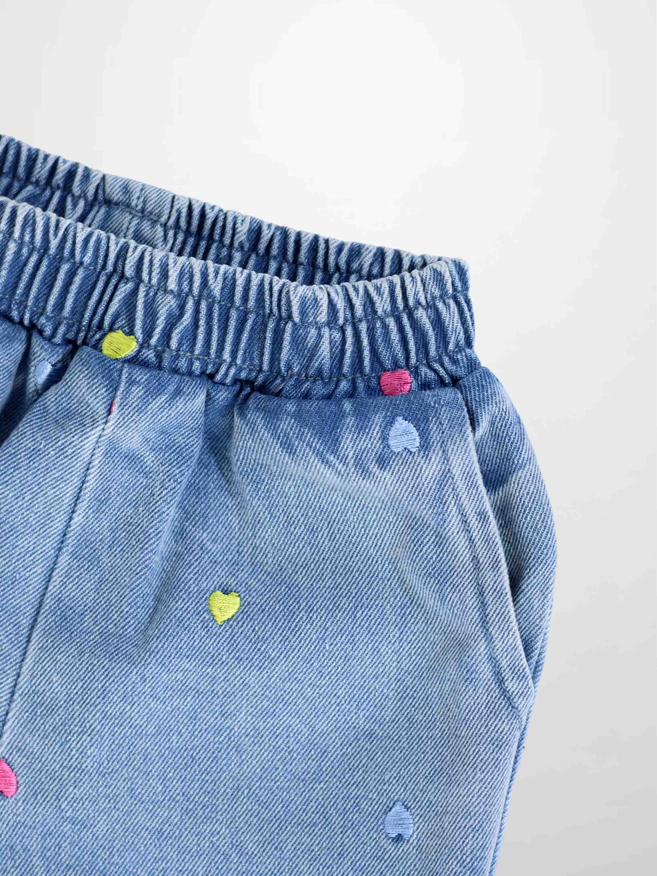 Embroidered heart denim shorts with colorful heart motifs and elastic waistband.