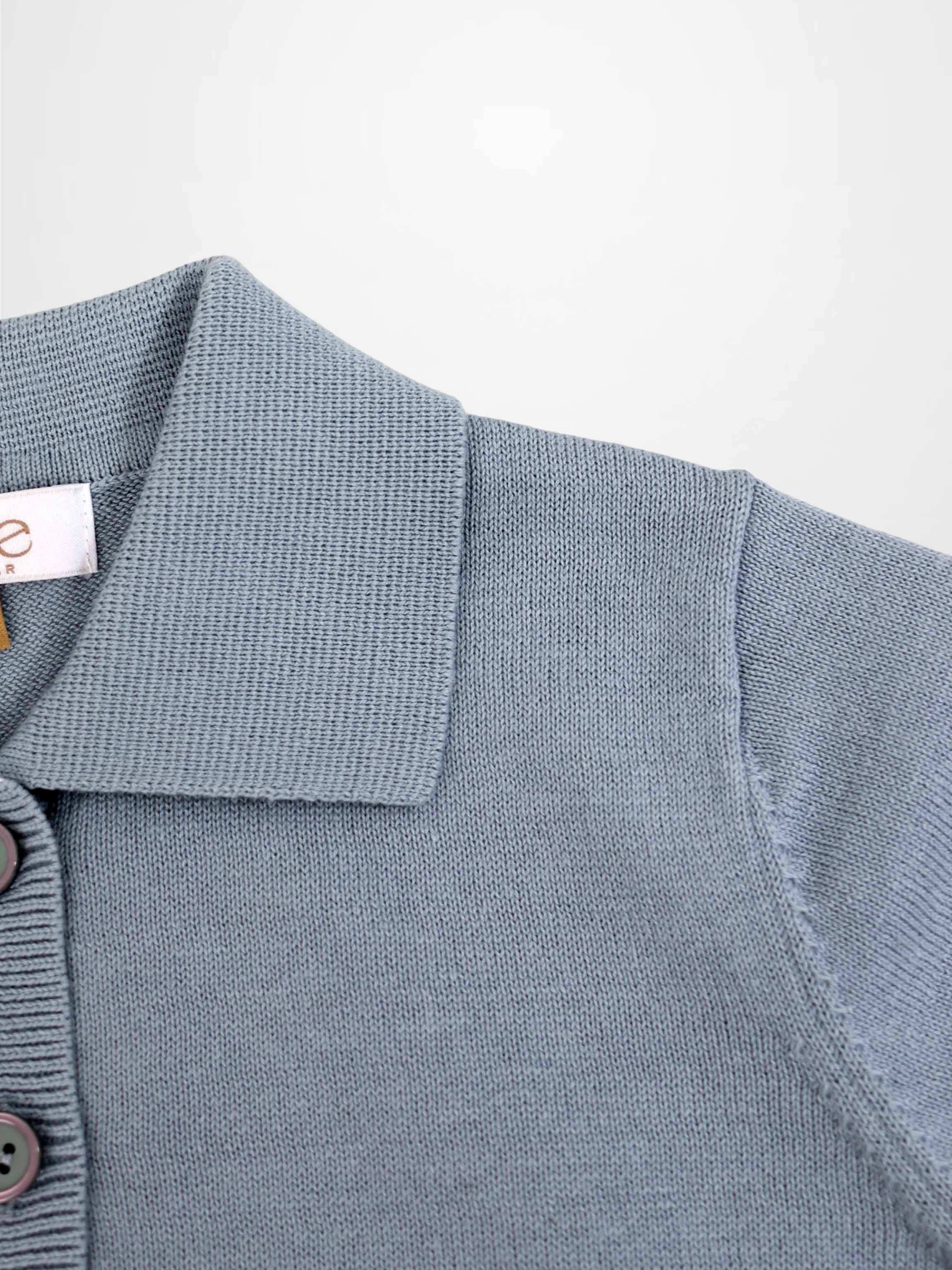 Light blue knit sweater with polo collar and button placket, close-up knit texture.
