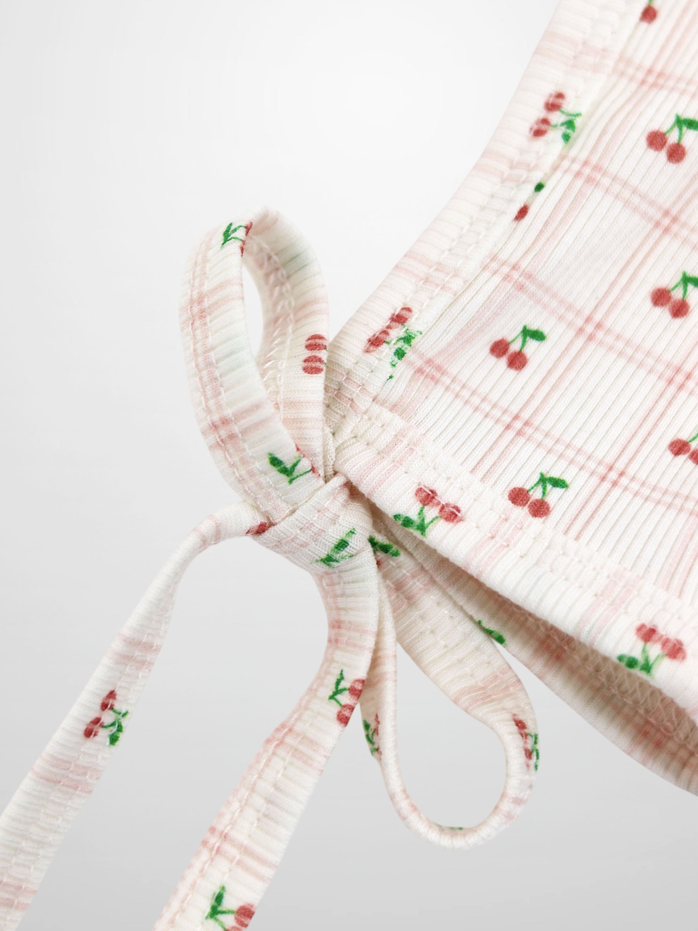 Cherry Window Bonnet for girls by Adee; pink-and-white thin-ribbed knit with cherry print and tie straps.