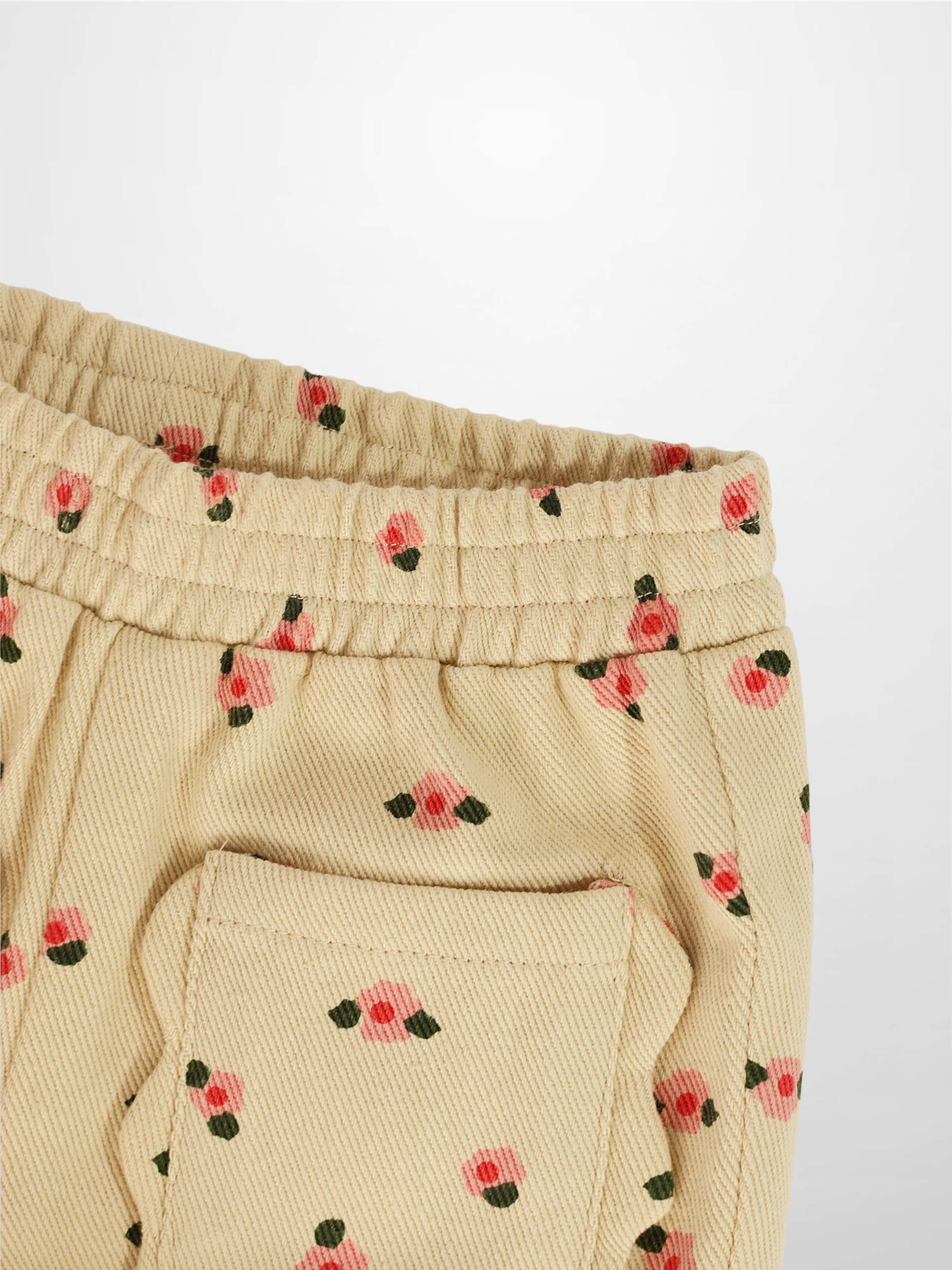 Tan floral shorts with pink flowers and green leaves, elastic waist and back pocket.