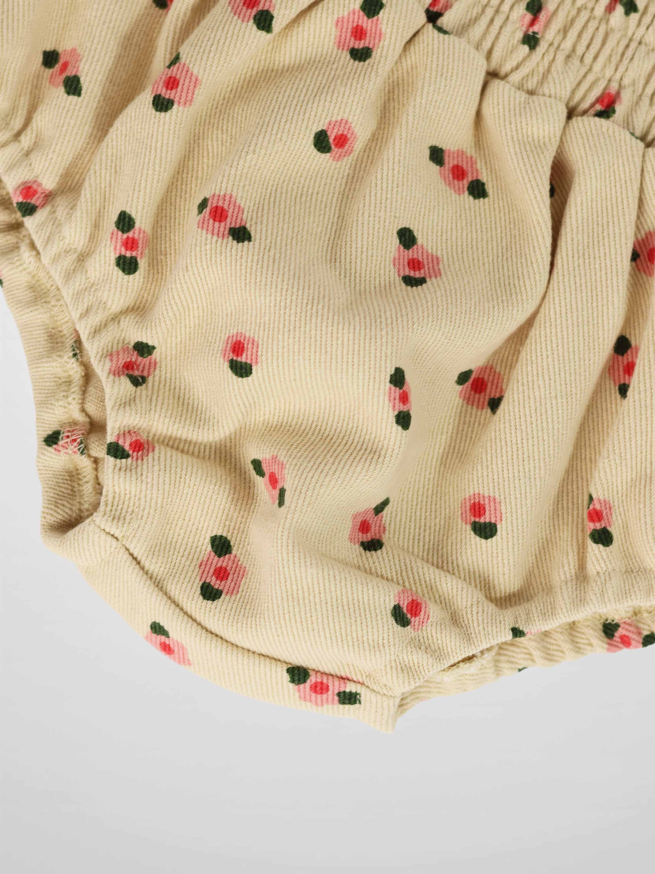 Tan floral bloomers for girls in ribbed fabric with pink flowers and green leaves, elastic waist and leg openings.