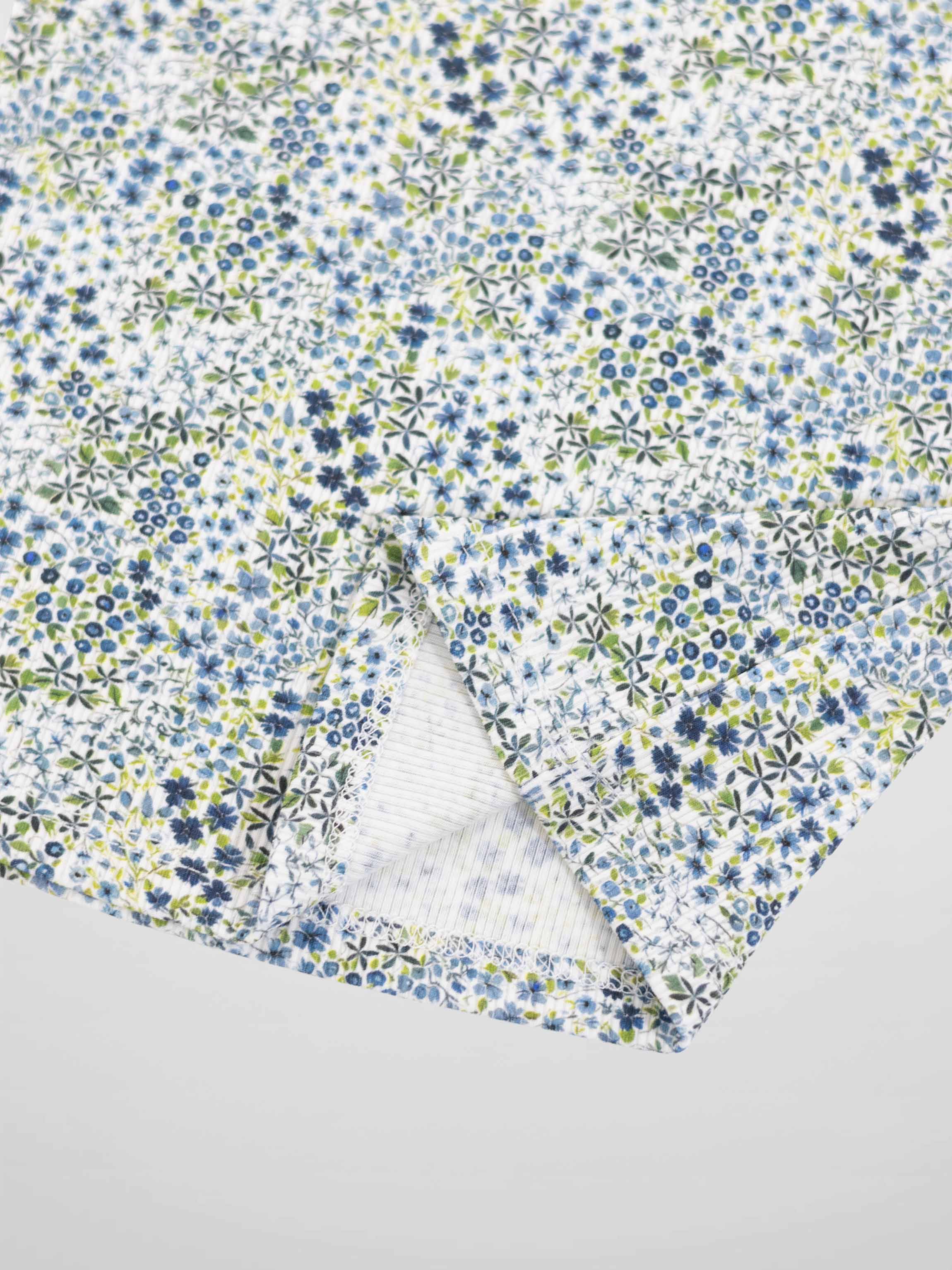 Blue floral pajama fabric with tiny blue and green flowers on white background.