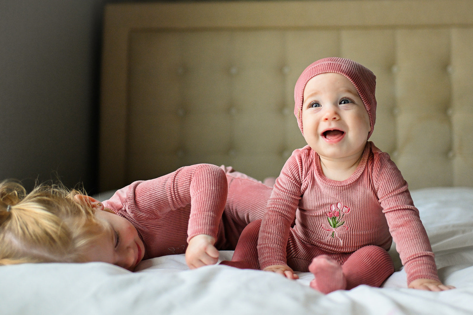cute baby girls playing in a bed with a pink jumpsuit footie with tulip flowers
