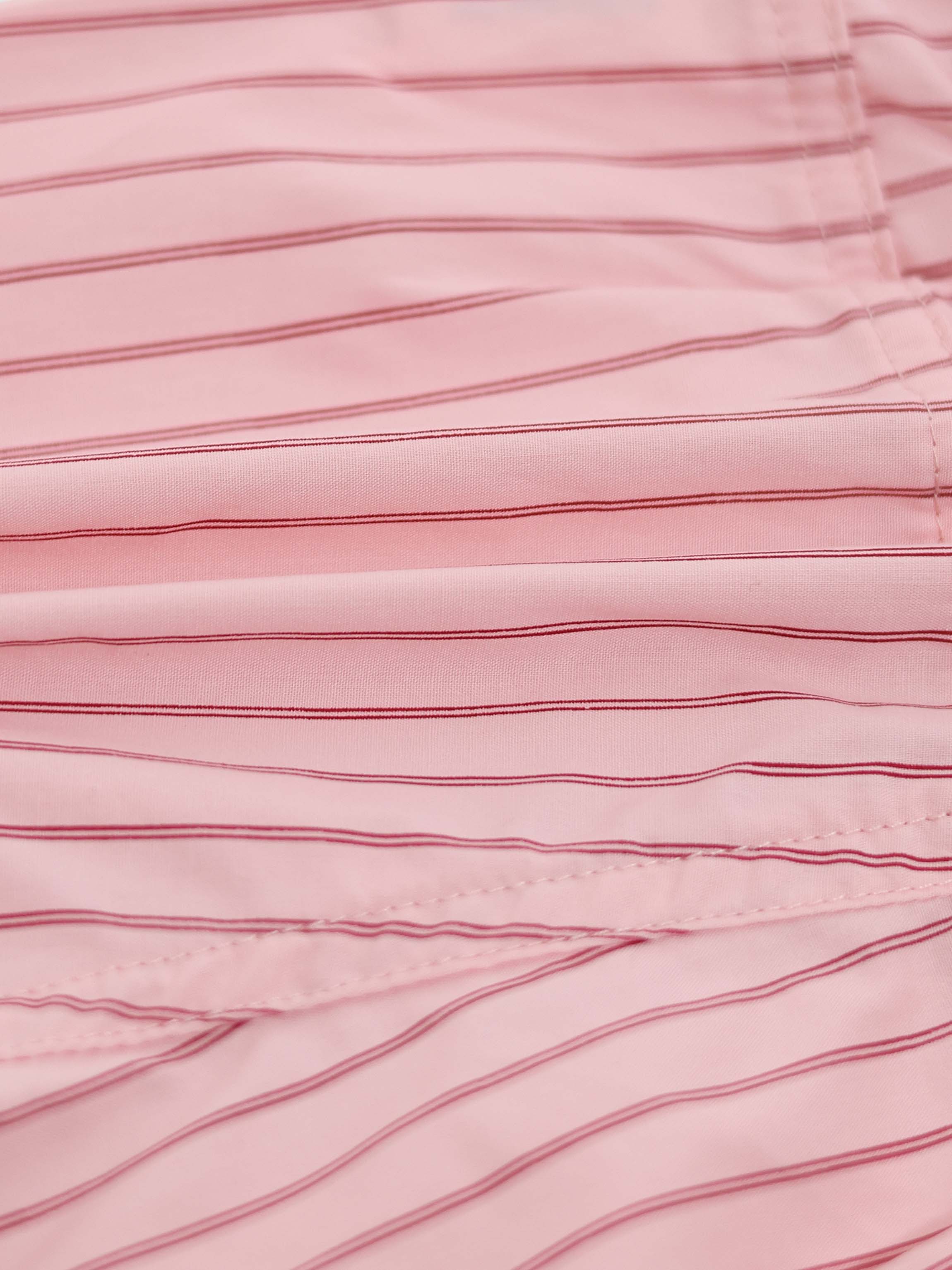 Close-up of pink striped cotton skirt fabric with thin red lines and visible hem stitching.