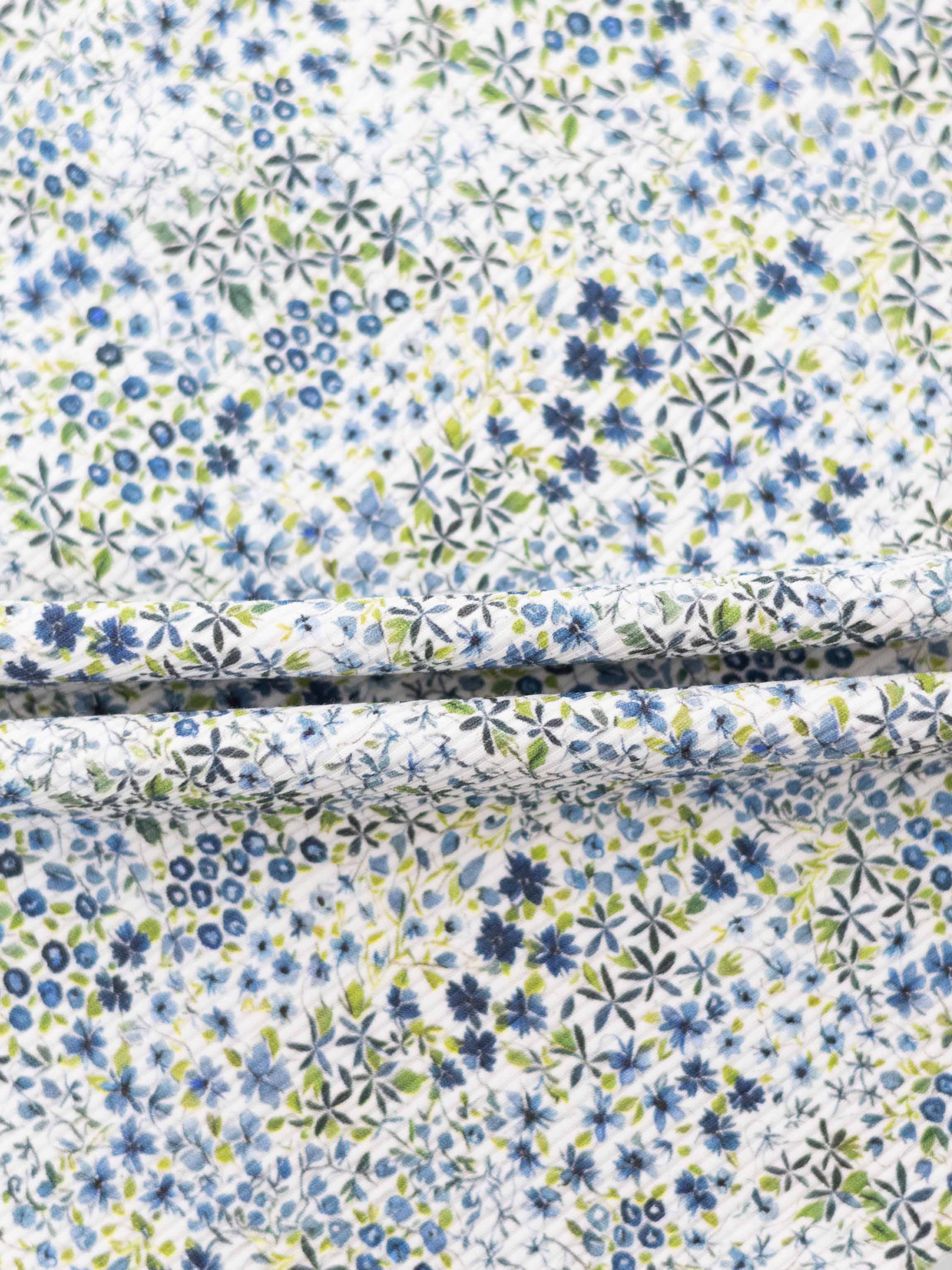 Blue floral pajama fabric with blue and green flowers on white background.
