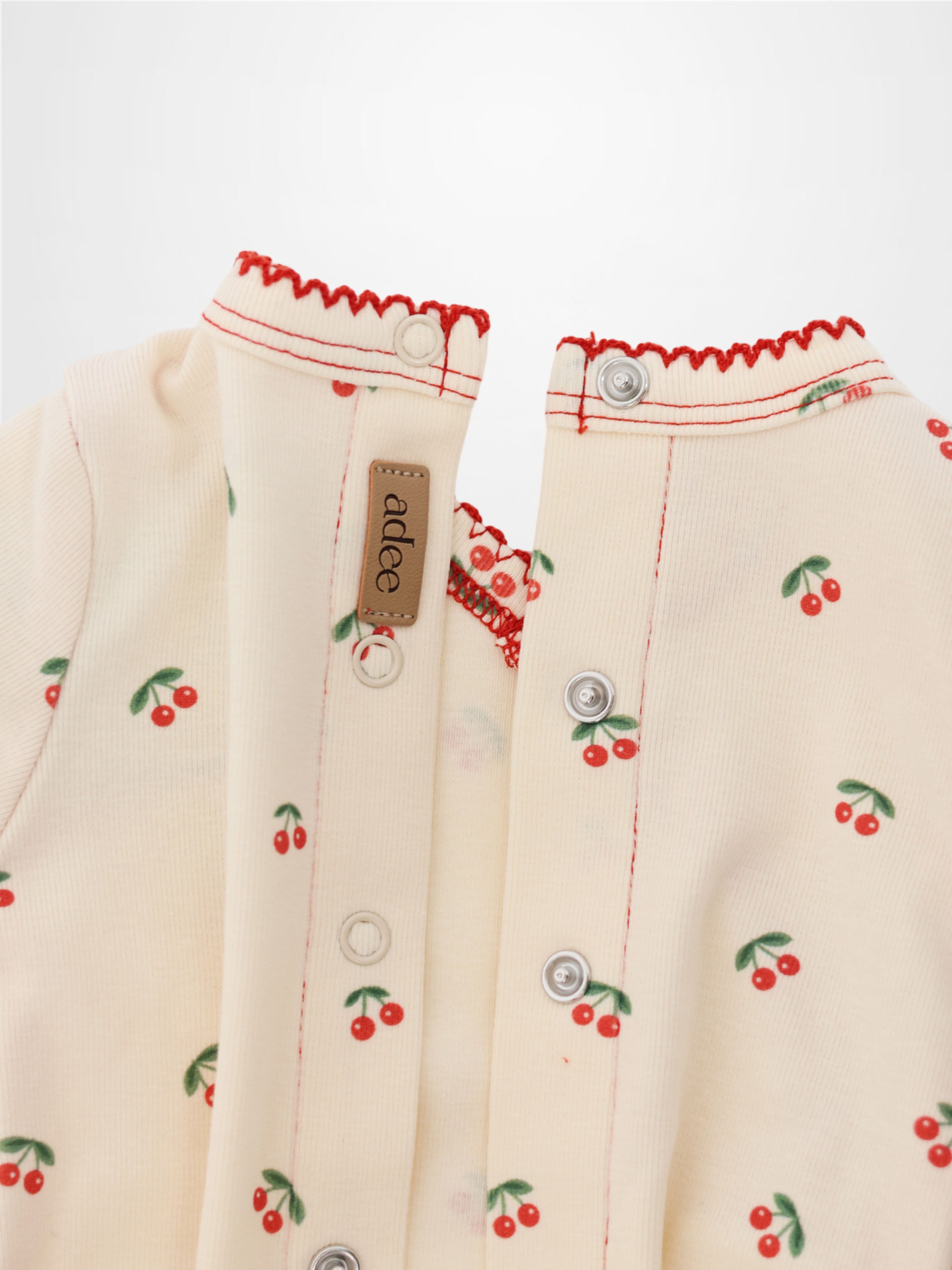 Red Cherry Stretchy girls top by Adee; cream fabric with red cherries and green leaves, front snaps.