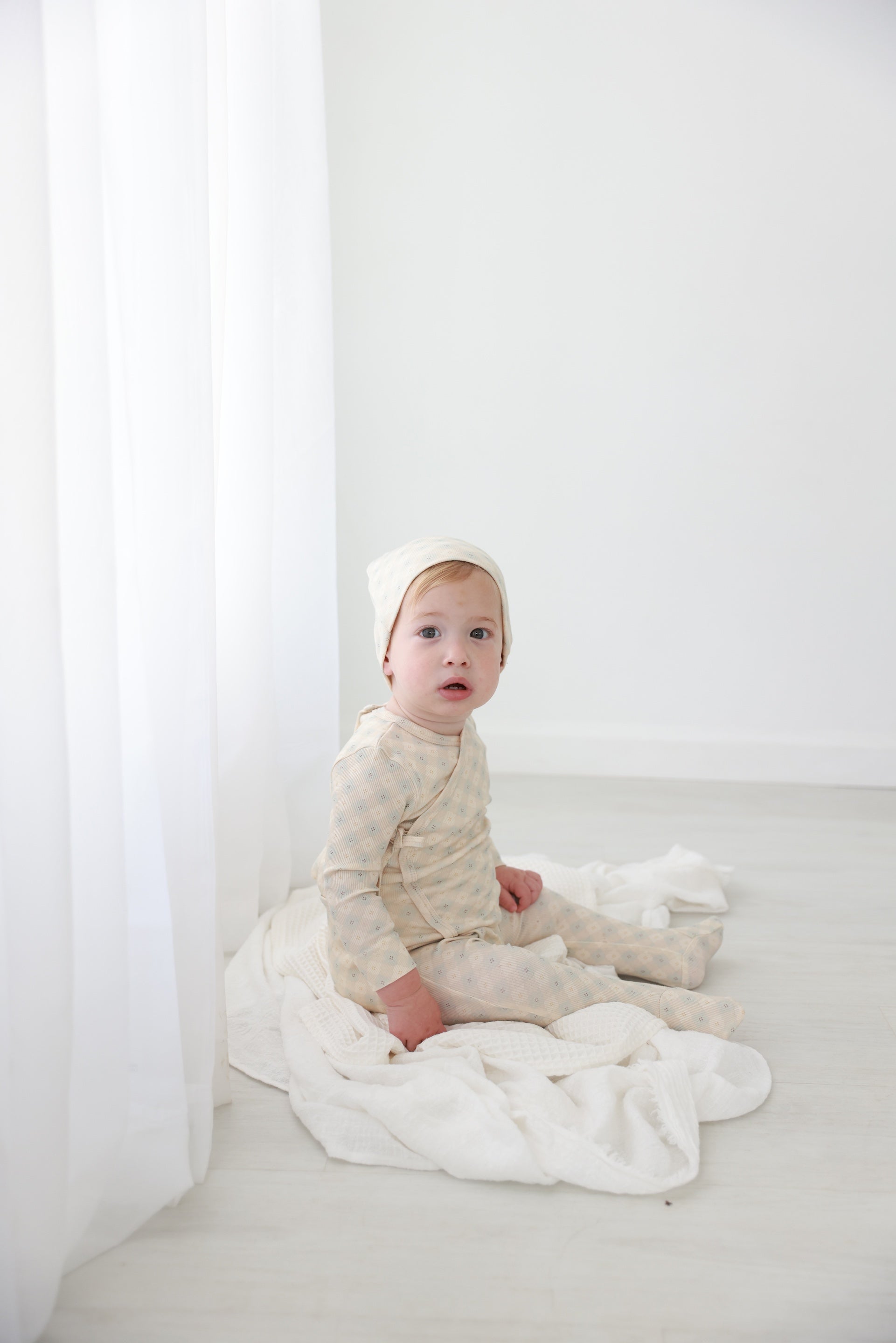 Little Button Blue layette set by Adee; cream-beige baby pajamas on white backdrop.