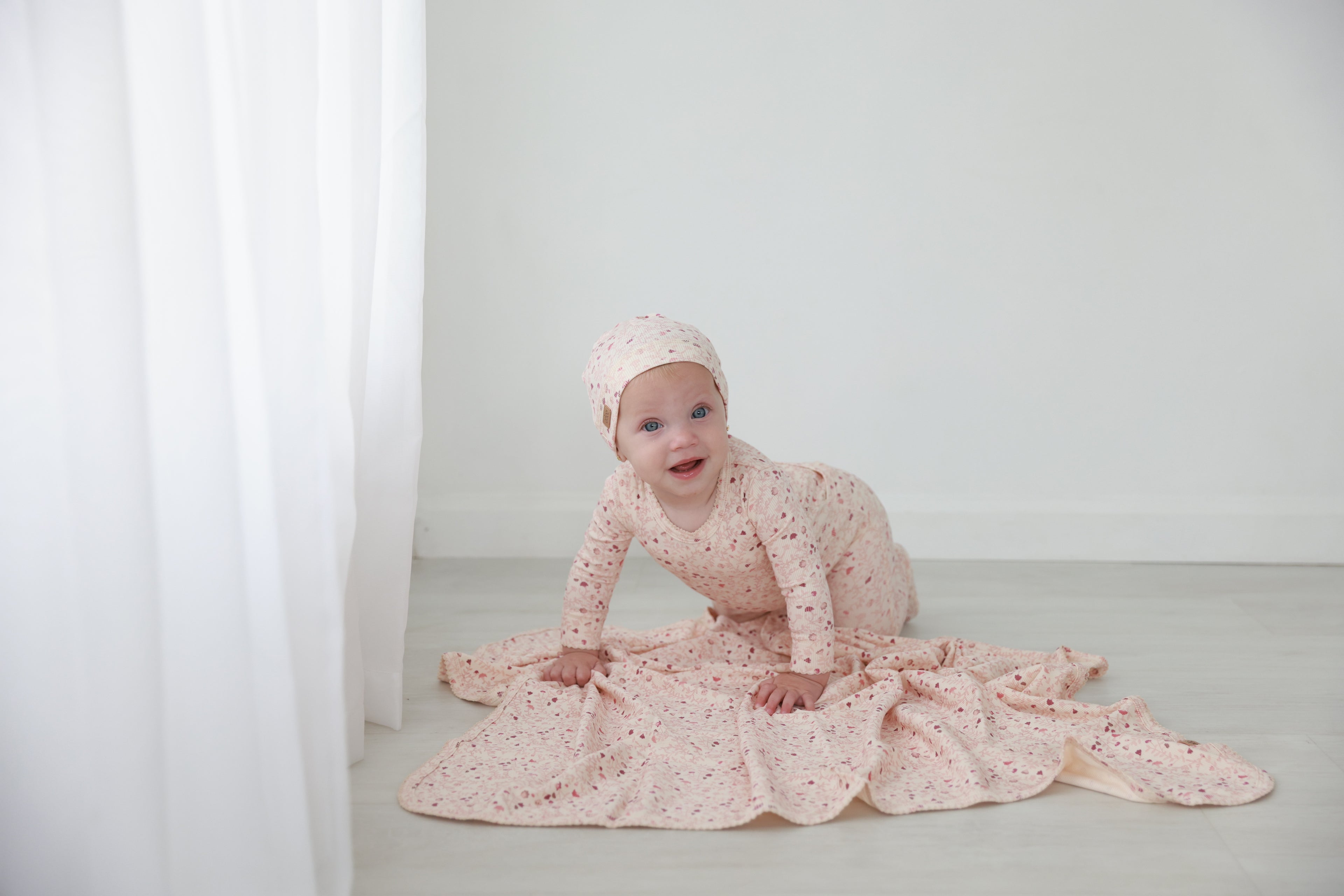 Garden Sprinkles Stretchy girls stretchies by Adee in pink floral print worn by a baby.