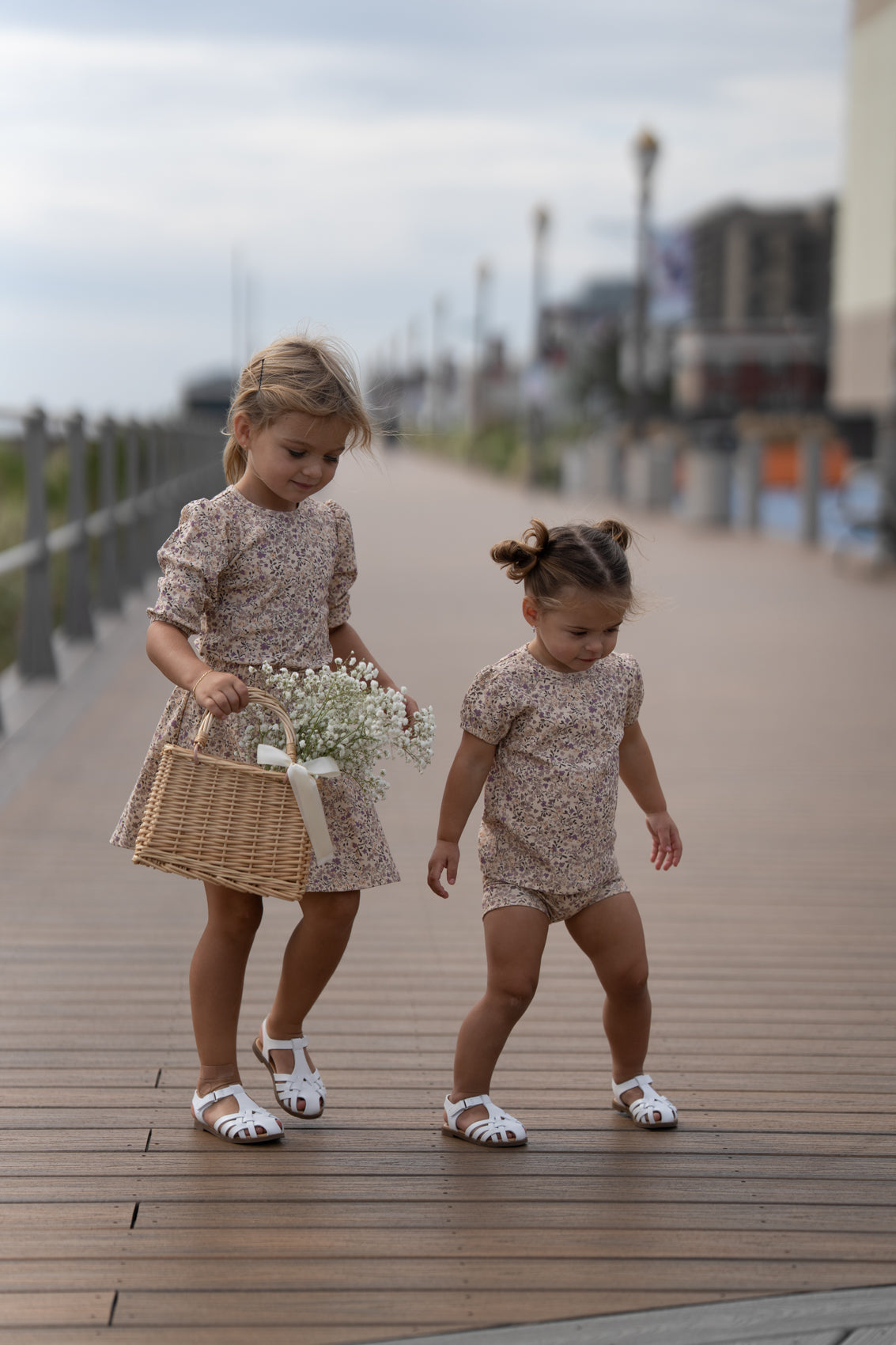 Purple Flower Short Sleeve Shirt by Adee; beige floral print girls tops worn by two kids on a boardwalk.