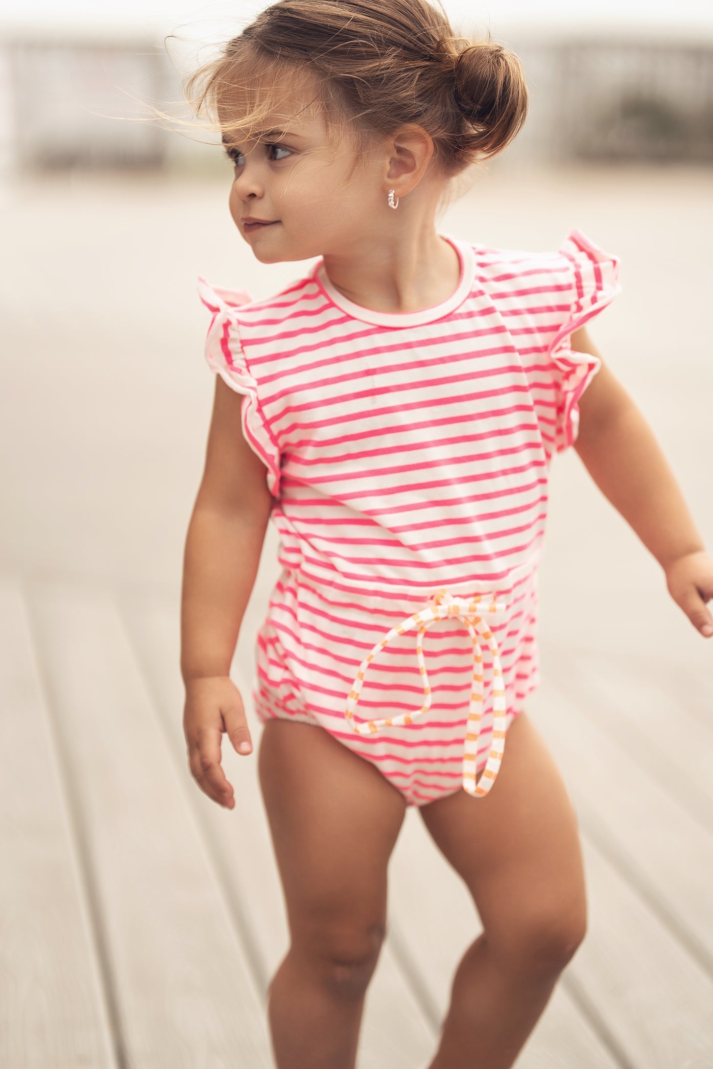 Neon pink striped girls romper by Adee with ruffled sleeves and drawstring waist