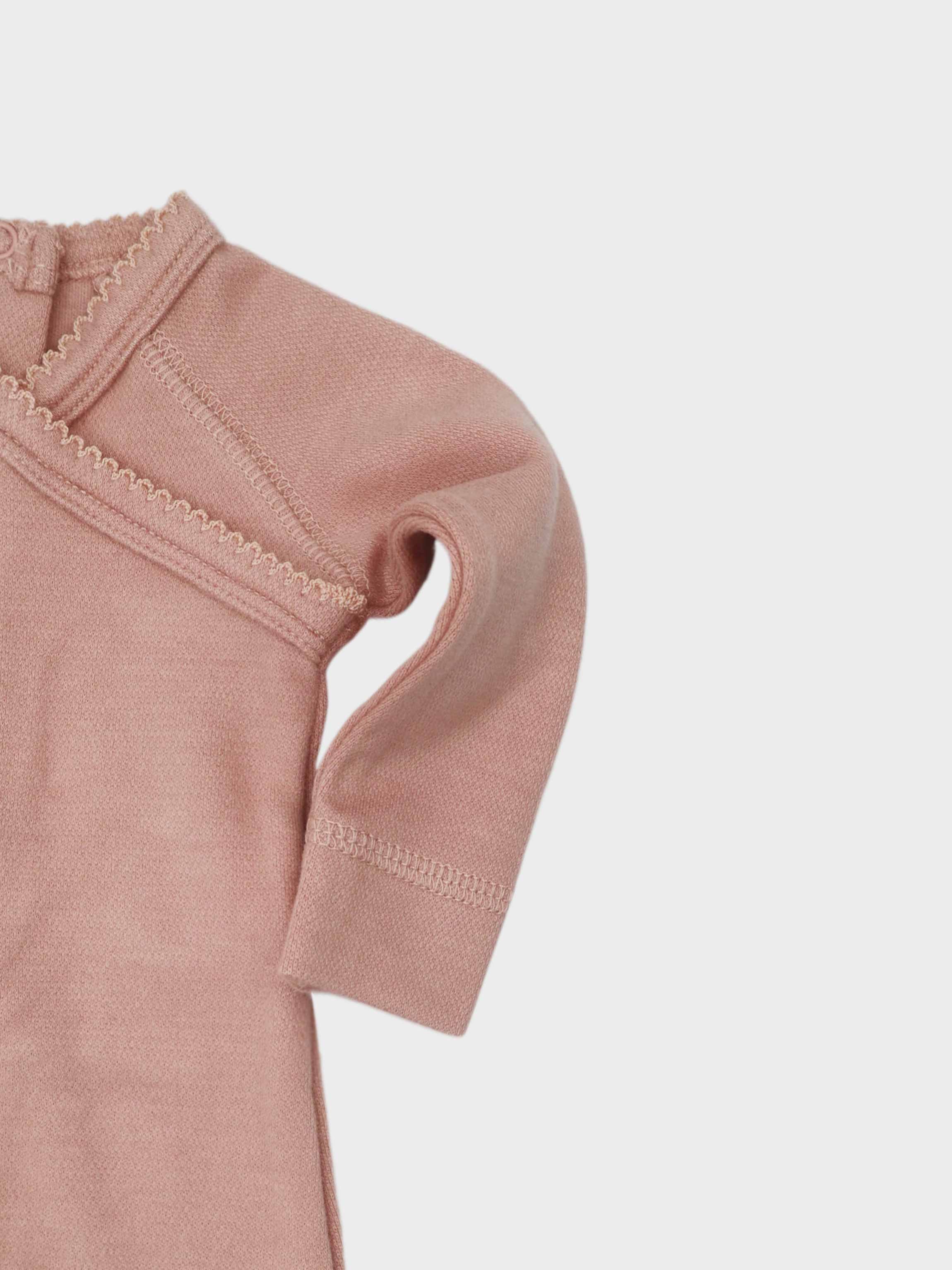 Girls stretchies pink jumpsuit sleeve close-up with zigzag stitch details.