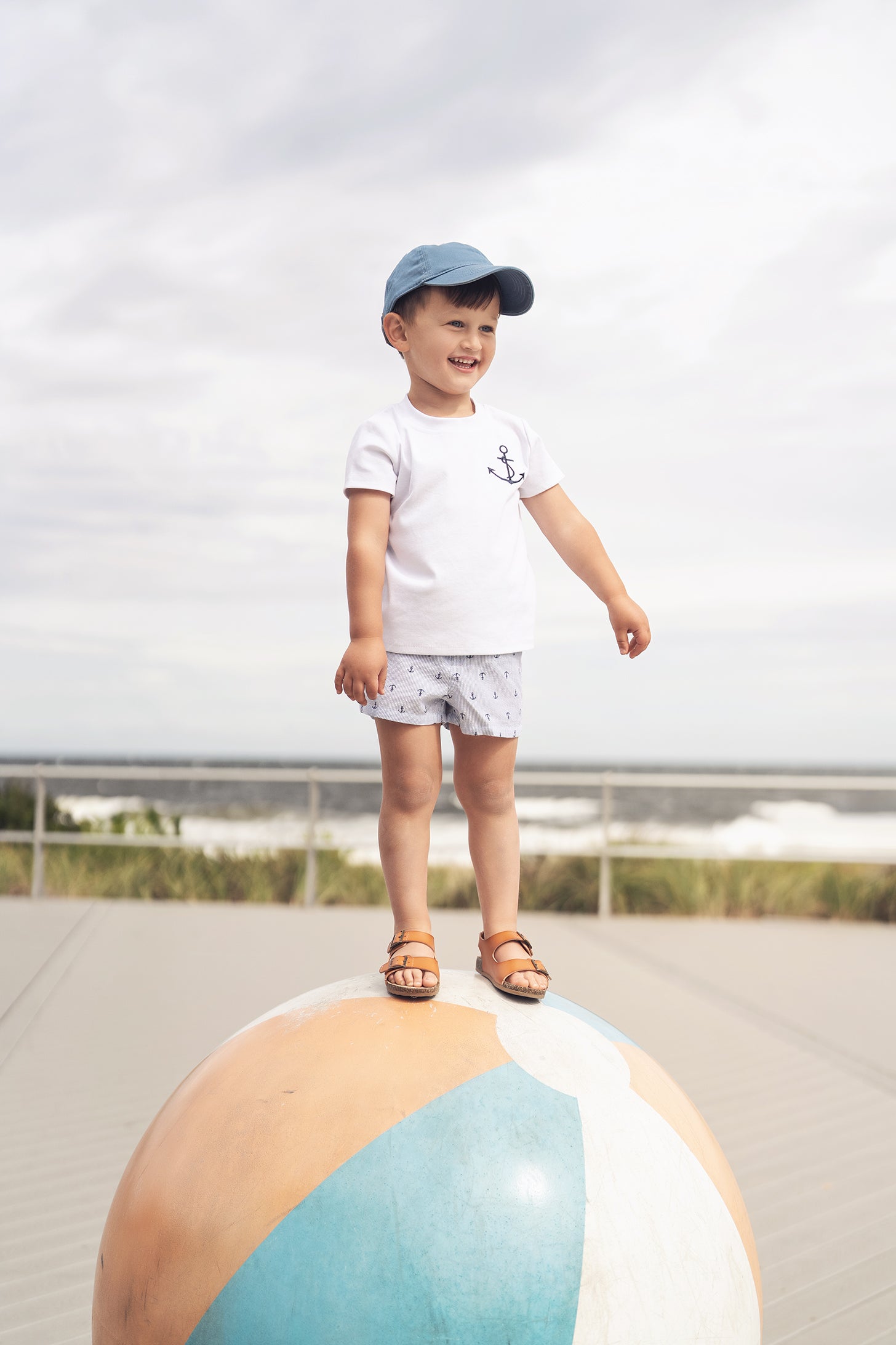 Child wearing white Embroidered Anchor Boxy Short Sleeve T-Shirt on a large beach ball