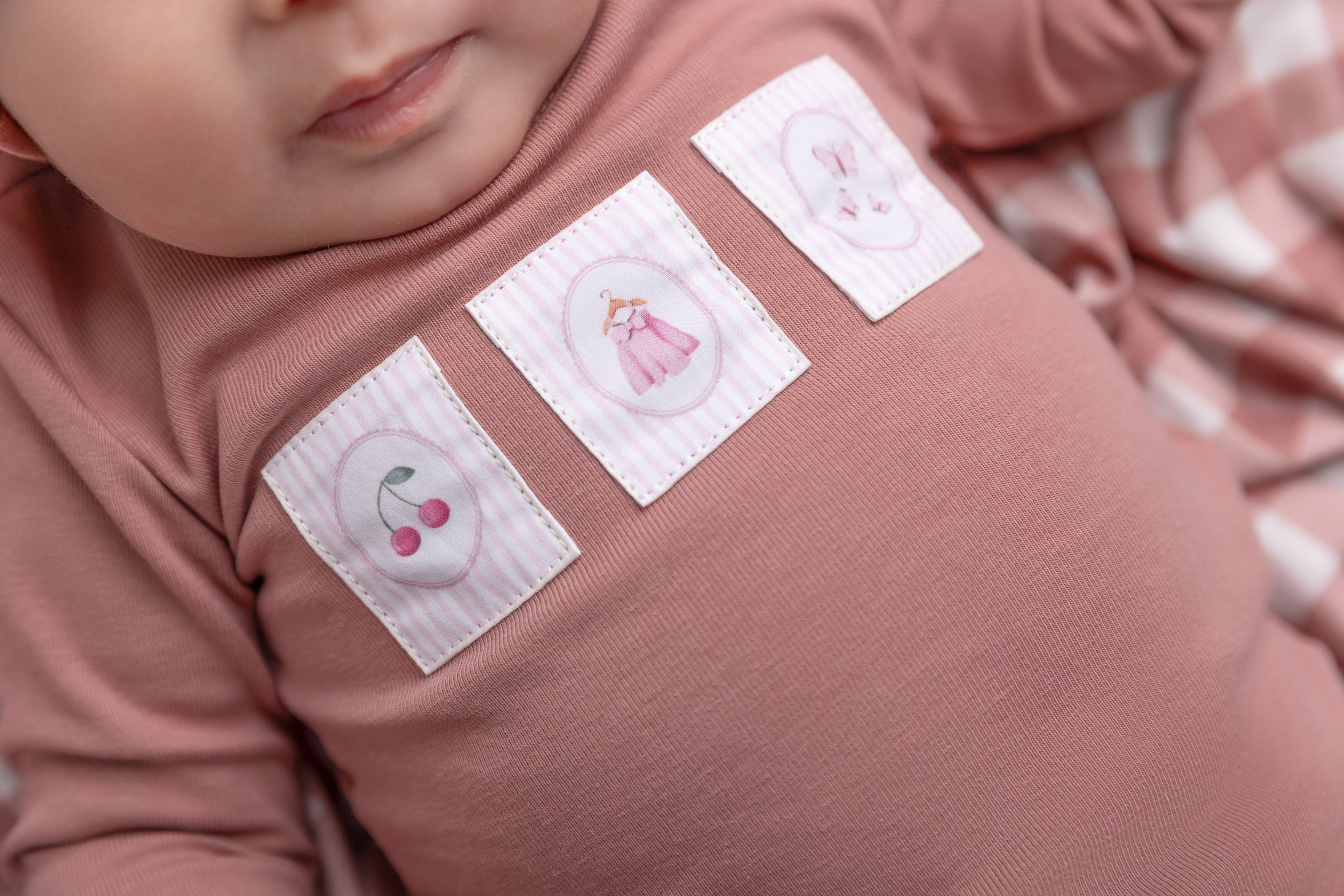 Cherry Frame Stretchy girls jumpsuit in muted pink with four pastel patch squares on chest.