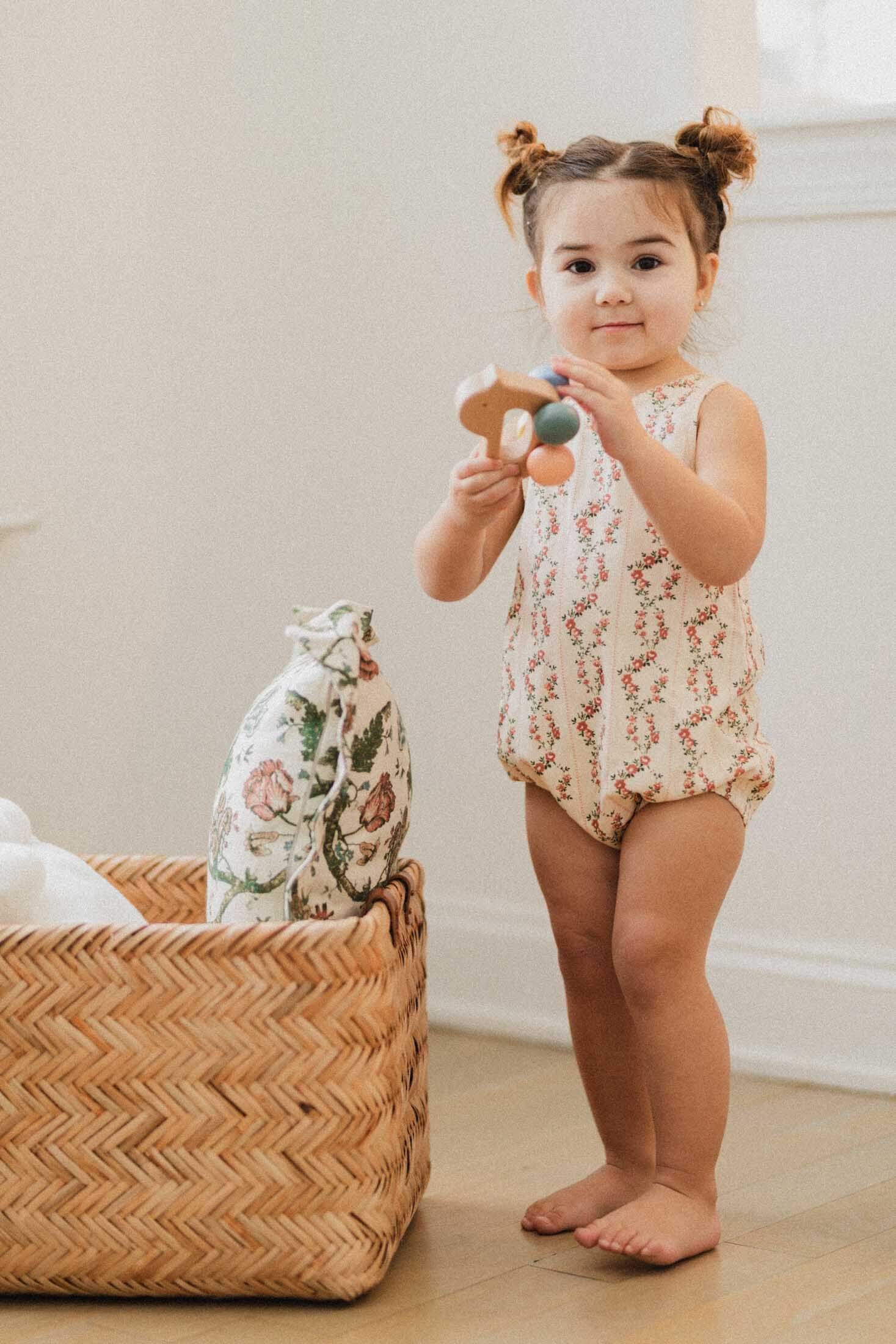 Toddler in floral romper playing.