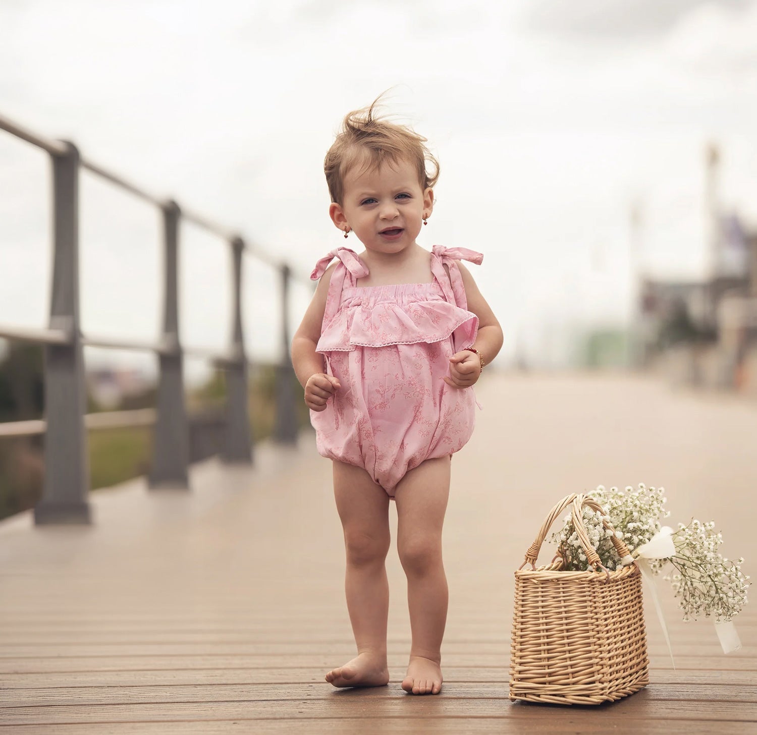 Two adorable infants wearing soft baby rompers, playing with toys on a cozy floor, showcasing stylish baby apparel.