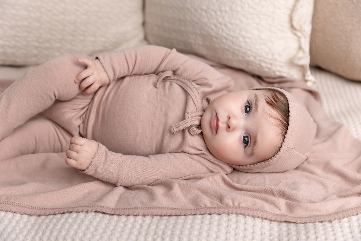 Newborn baby in floral layette set wearing a bonnet, showcasing comfort and style.