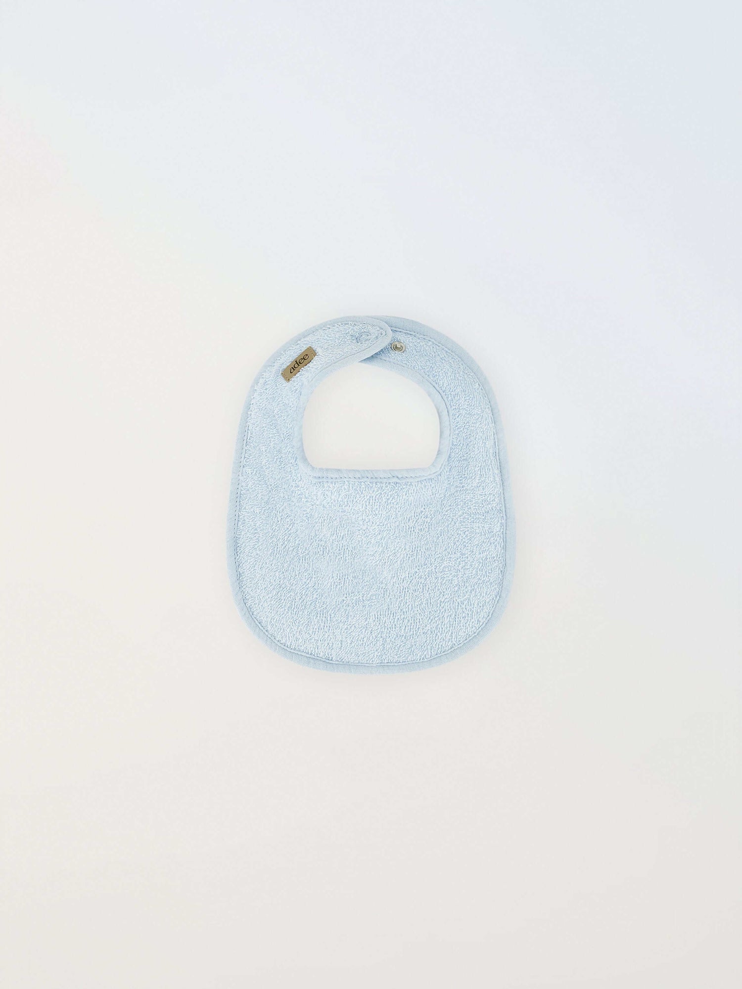 Small blue Adee bib for boys in terry cloth with brand tag visible