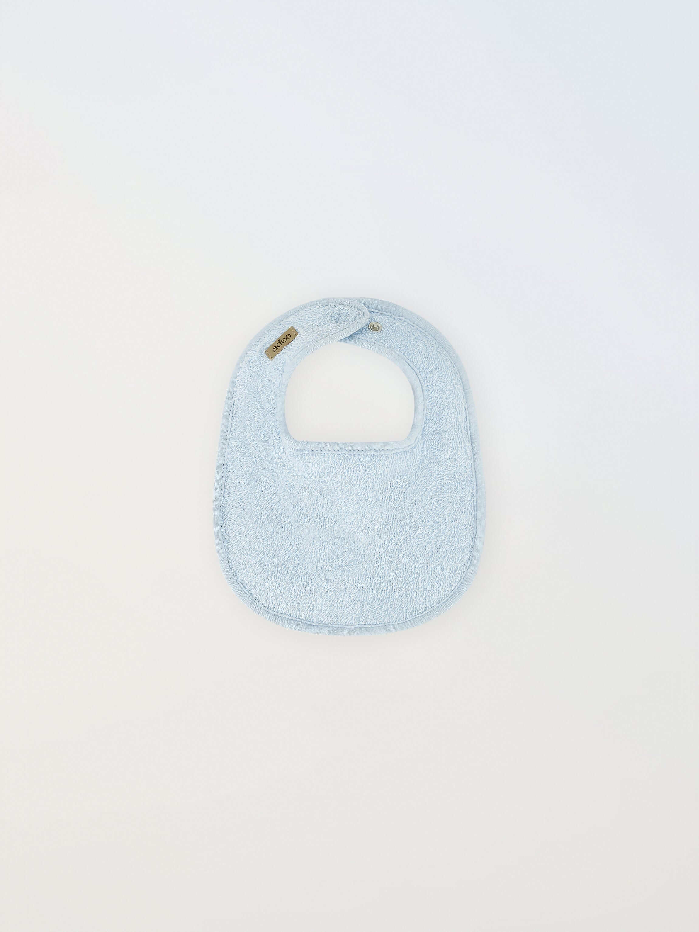 Small blue Adee bib for boys in terry cloth with brand tag visible