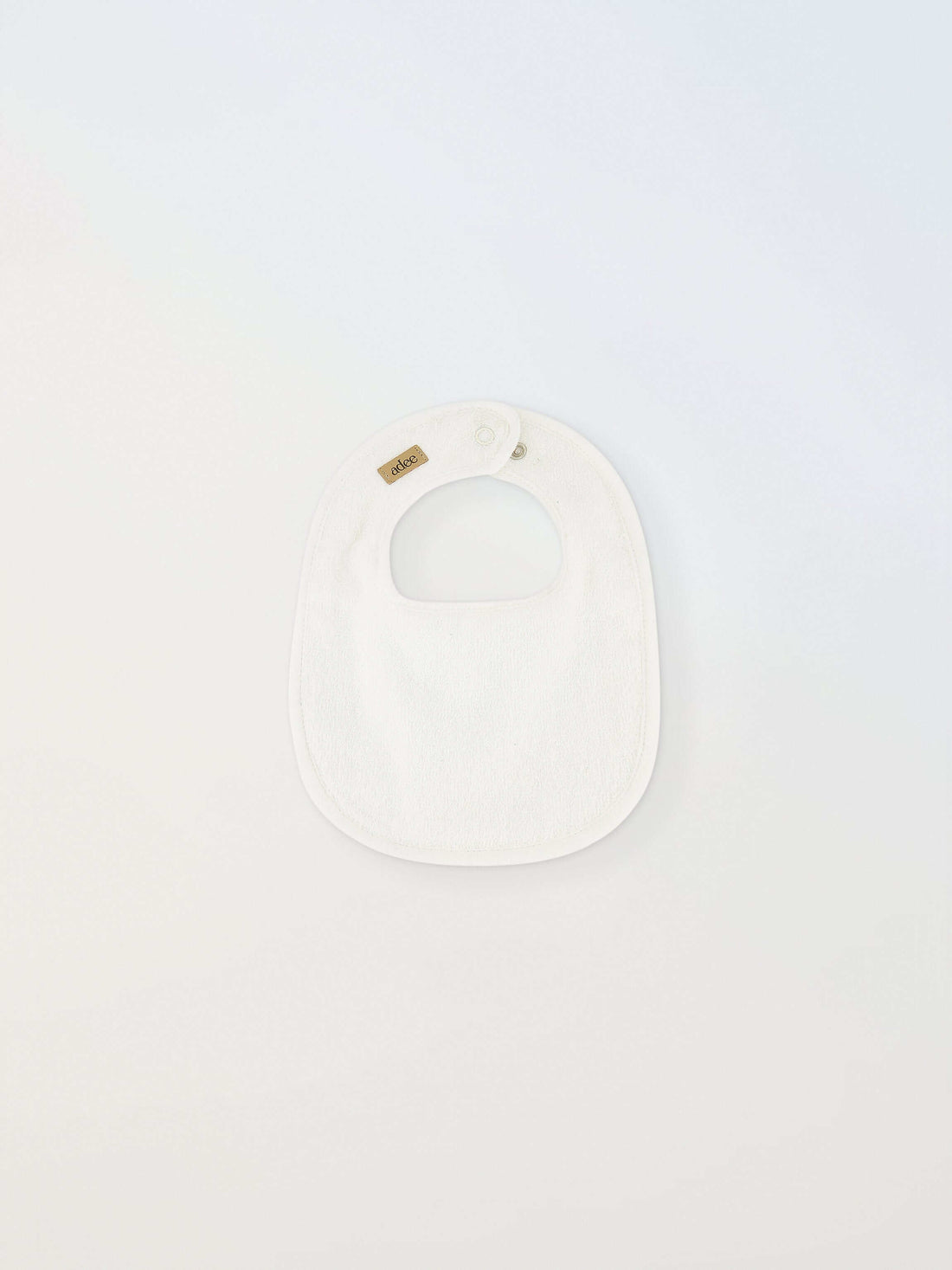 Small white Adee bib for infants; unisex with brown Adee label.