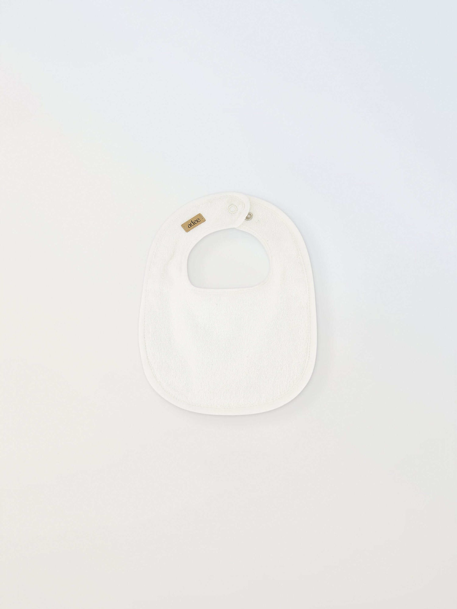 Small white Adee bib for infants; unisex with brown Adee label.