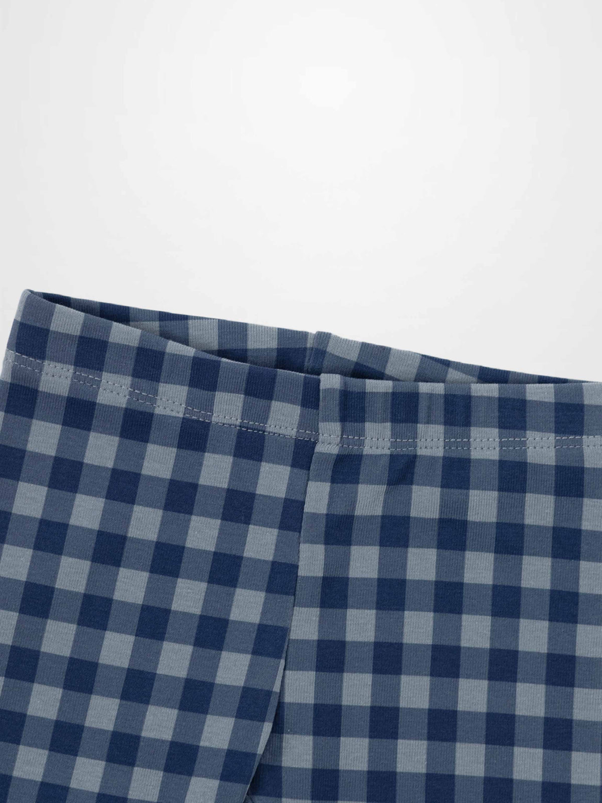 Blue gingham pajamas fabric close-up showing a checkered pattern and waistband seam.