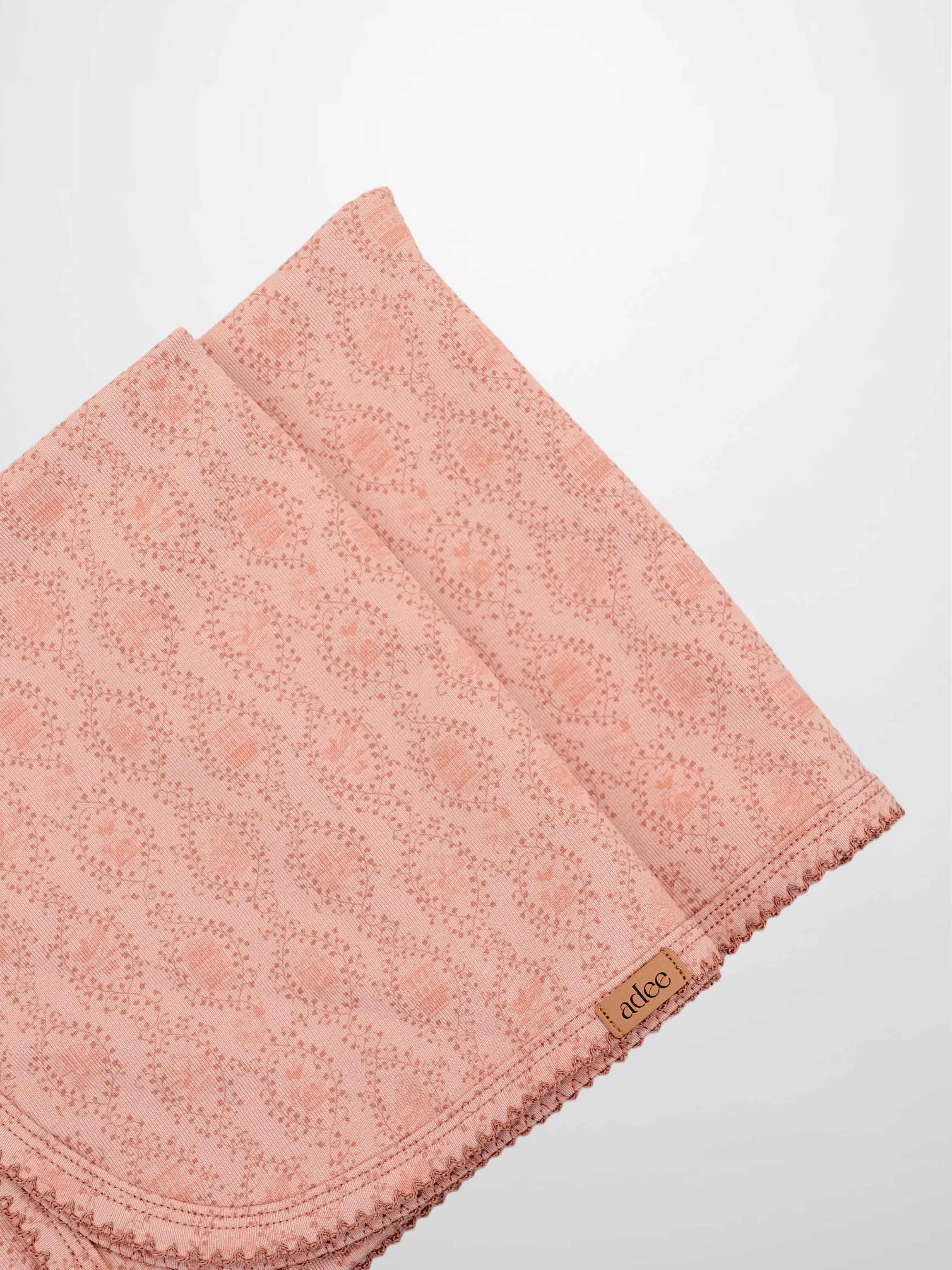 Pink Charm Blanket, light pink Adee receiving blanket with a scalloped edge.