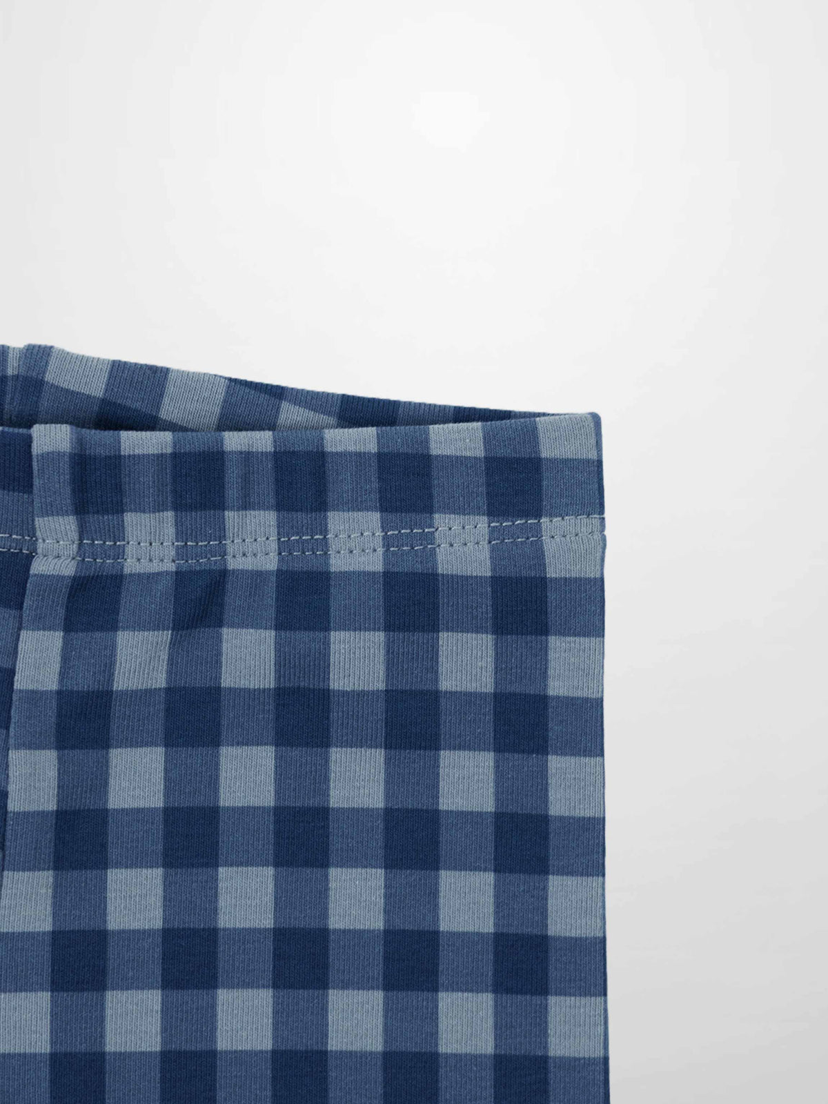 Blue gingham pajama fabric close-up showing checkered pattern and waistband stitching.