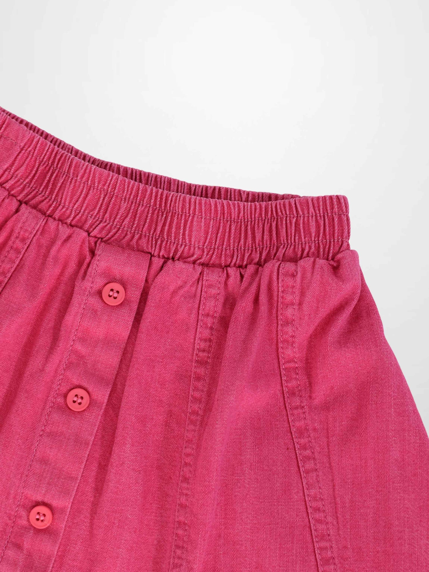 Paneled pink denim skirt with elastic waistband and button placket.