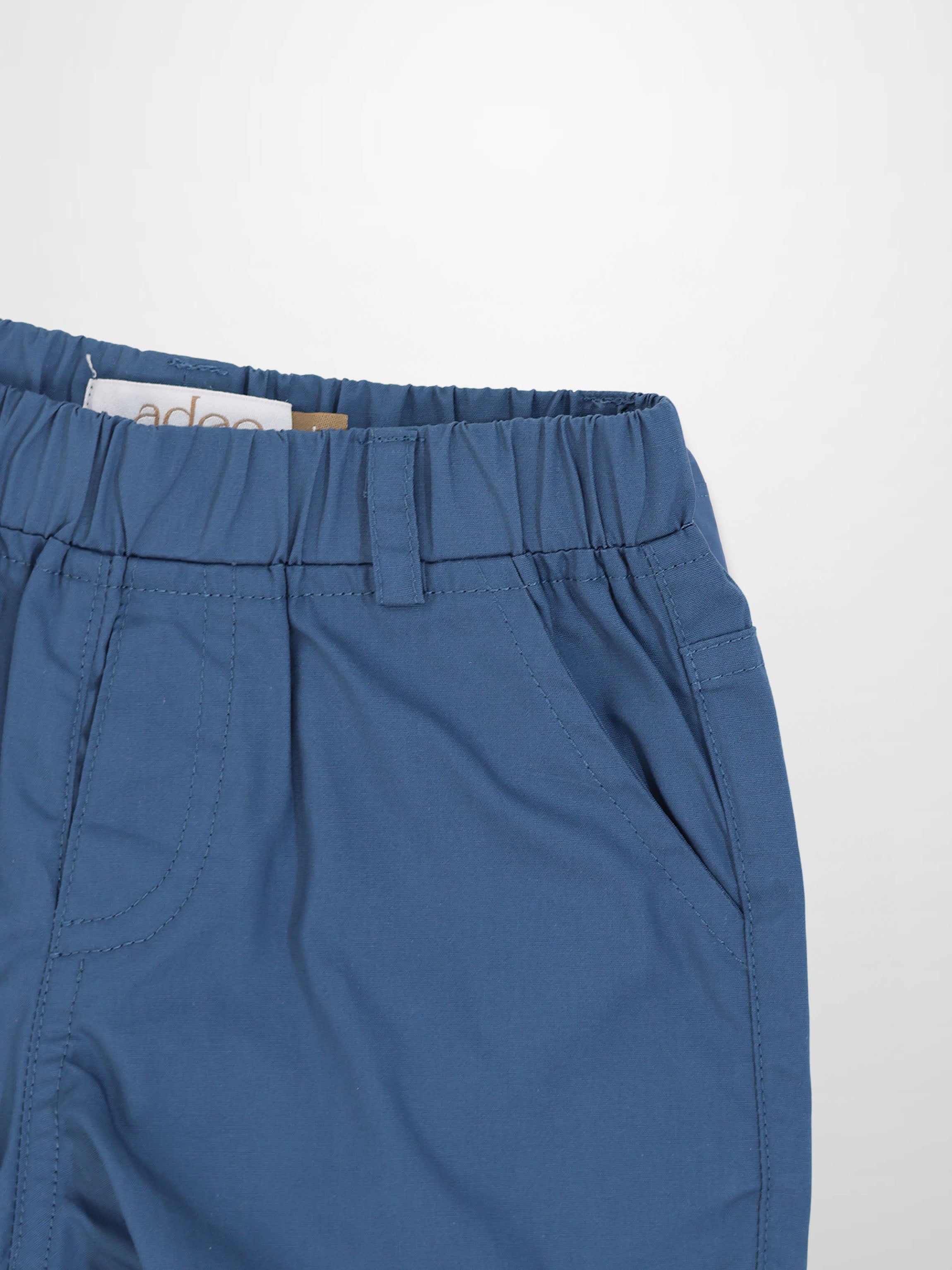 Blue cotton shorts with an elastic waistband, belt loop, and curved front pocket.