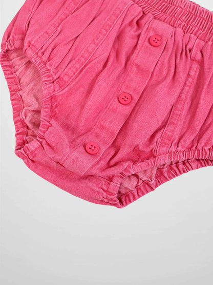 Paneled pink denim bloomers with elastic waist and pink button placket.