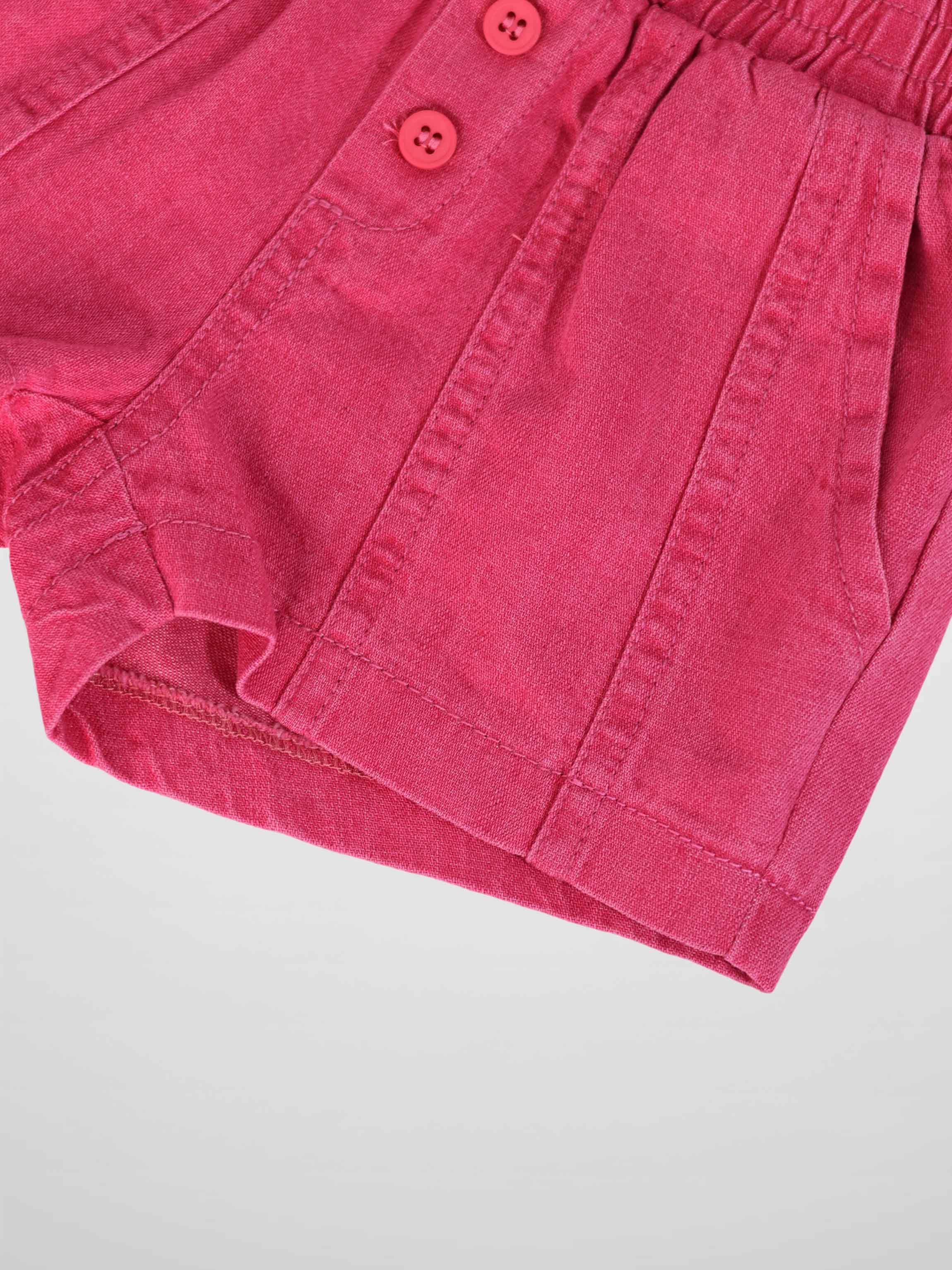 Pink denim paneled shorts with elastic waist and button-front closure.