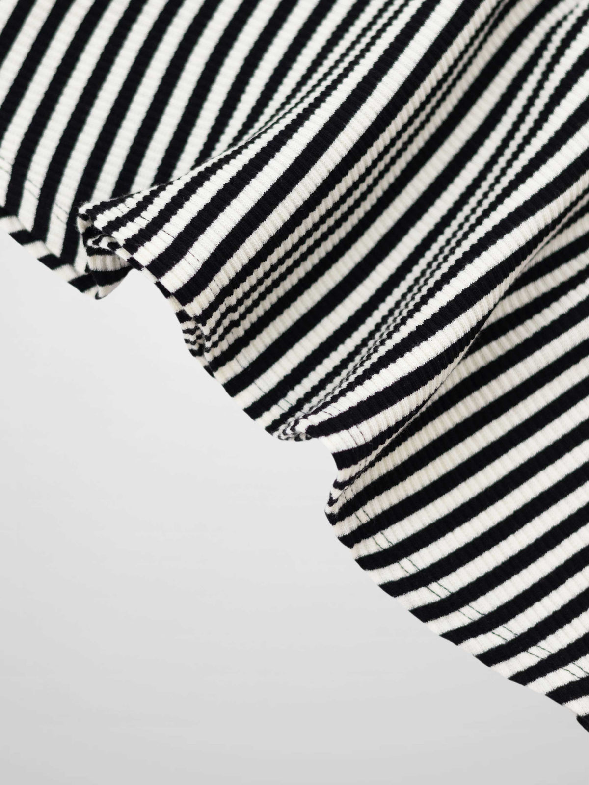 Close-up of black and white striped ribbed fabric with a curved hem