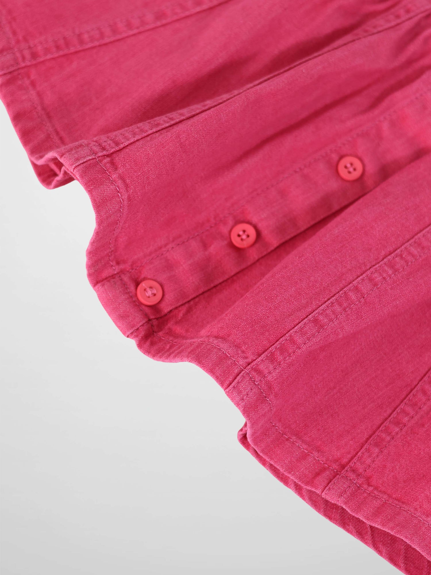 Pink denim paneled skirt close-up with pink buttons along the seam.