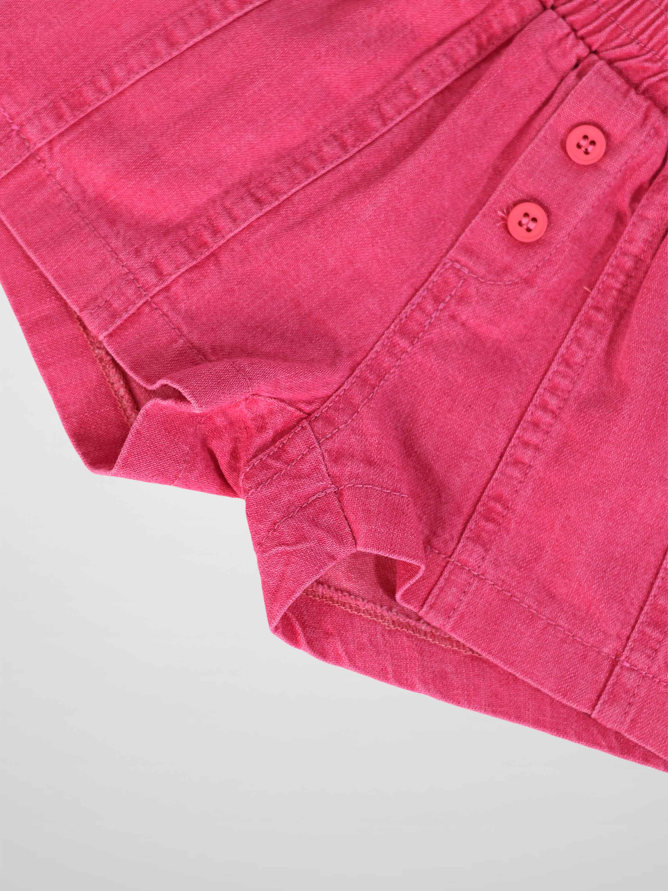 Paneled pink denim shorts with two-button waist detail.