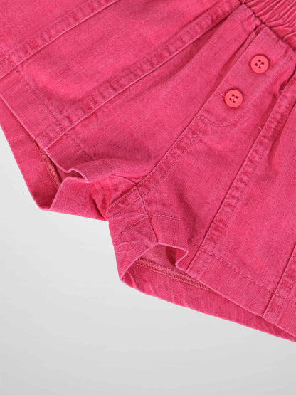 Paneled pink denim shorts with two-button waist detail.